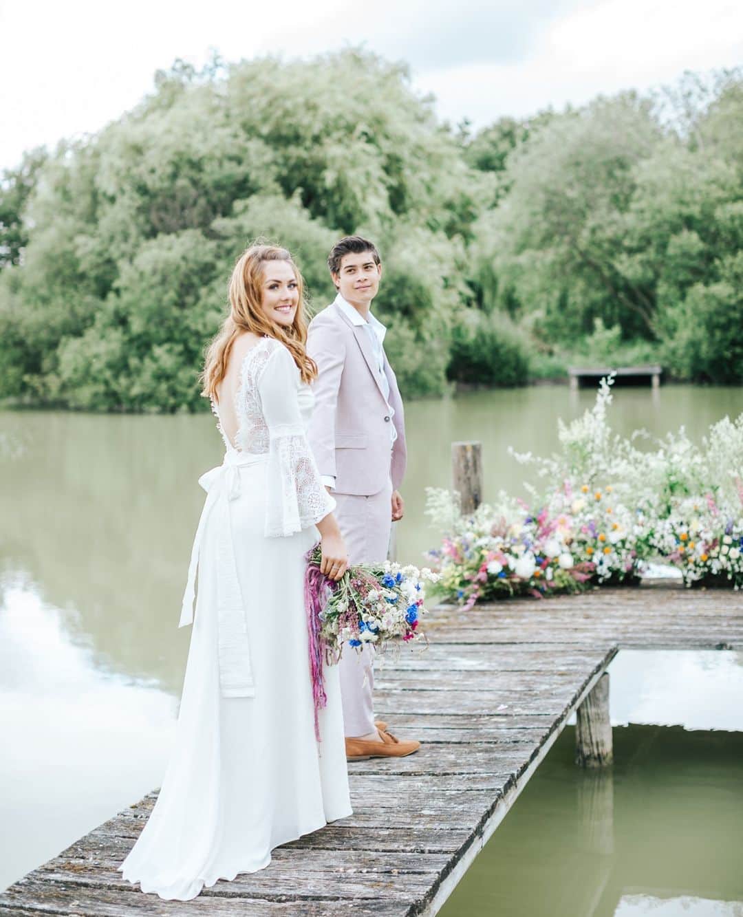 ミナのインスタグラム：「Love the wild flower arrangements by @saras.events.flowers⁠ in this outdoors wedding inspired photo shoot with pink, purple and blue colour scheme. Our Willow dress is the perfect dress when you're getting married surrounded by nature! 😍 Check out the rest of the gorgeous pictures featured on @rockmywedding blog. Link in bio.⁠ ⁠ Photo & Film - @nikkismoments⁠ Venue - @thebarnatbrookendgreenfarm⁠ Wedding Planner & Stylist - @misscarlysleandco_events⁠ Florist & Stylist - @saras.events.flowers⁠ Stationery - @tiggityboodesign⁠ Cake - @labellecakecompany⁠ Prop hire - @wrenprophire⁠ Balloon arch - @creativedecorations⁠ Models - @modelcouple_d.s_ ⁠ ⁠ ⁠ ⁠」