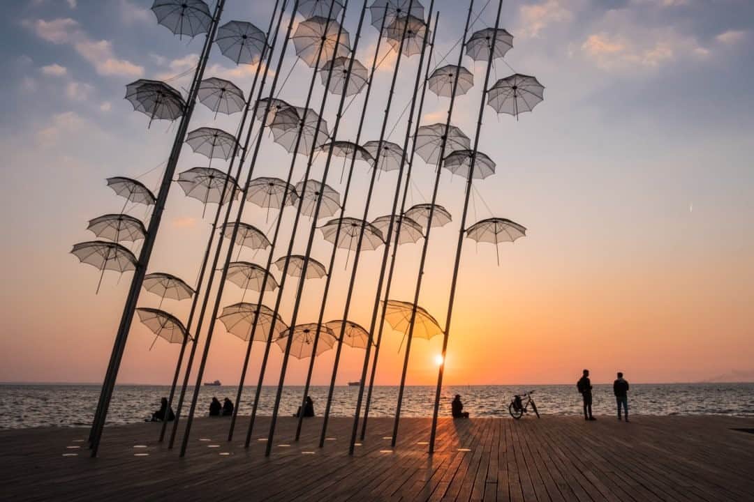 National Geographic Travelさんのインスタグラム写真 - (National Geographic TravelInstagram)「Photo by @francescolastrucci / The sun sets over the Thermaic Gulf of the Aegean Sea in Thessaloniki’s new seafront, filtered by the iconic “Umbrellas” sculpture. The work by Greek artist George Zongolopoulos was first introduced in 1993 at the 45th Venice Biennale and subsequently placed on the waterfront of Thessaloniki in 1997, when the city was named the European Capital of Culture. Since then its inhabitants have adopted the sculpture, which has become a landmark of the city. The sculpture appears ethereal, delicate, and ever changing according to the light that passes through it. Vibrant Thessaloniki is the most important city in northern Greece, and it rivals Athens as a cultural center of the country. Its geographical position as a bridge to the East has been strategic since ancient times for the unfolding of its history, making it a hub of interests, trade, and cultures. Follow me @francescolastrucci for more places, daily life, and stories around the world. #greece #gradient #dailylife」11月3日 16時39分 - natgeotravel