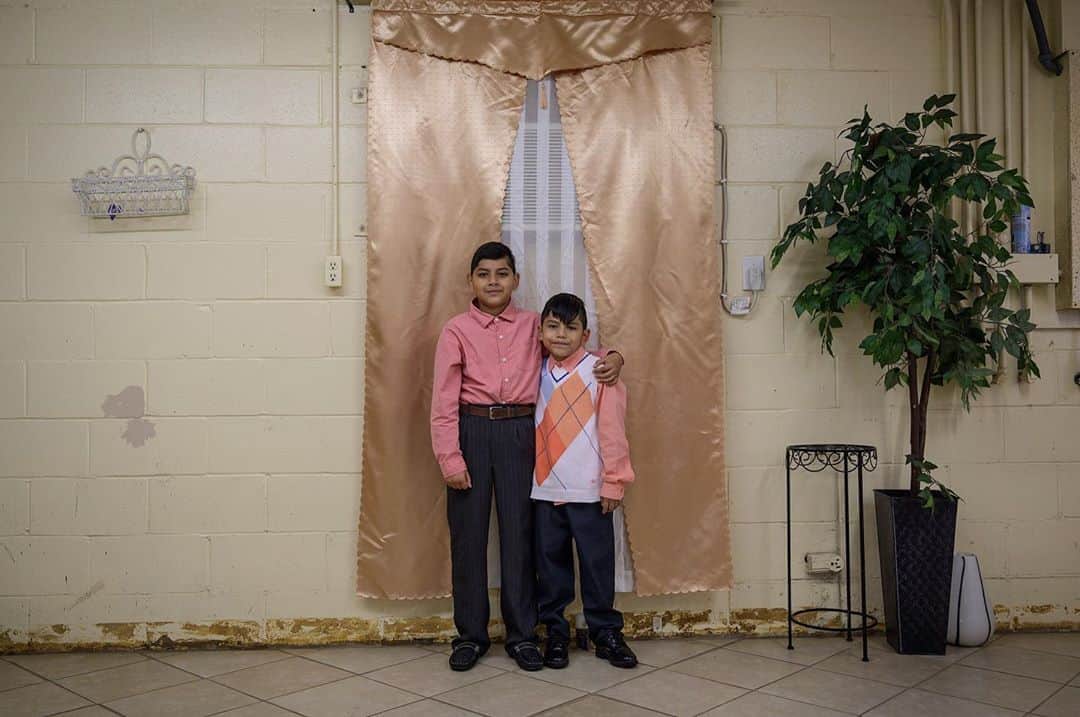 National Geographic Creativeさんのインスタグラム写真 - (National Geographic CreativeInstagram)「Photo by @andreabruce / Daniel Jorge, 10, and Abisai Jorge, 8, stand in their church, Iglesia Apostolica de la Fe Un Cristo Jesus, in a former gas station, in Newton Grove, North Carolina.  Their sister (not pictured) said their town is very small and a food desert, with less than 100 people in her graduating class. "Most people here are farmers—cotton and tobacco," she said. "We sometimes help with field work during the summer."  They said their grandparents moved here from Mexico and had 15 children and now have 56 grandchildren.」11月3日 20時02分 - natgeointhefield