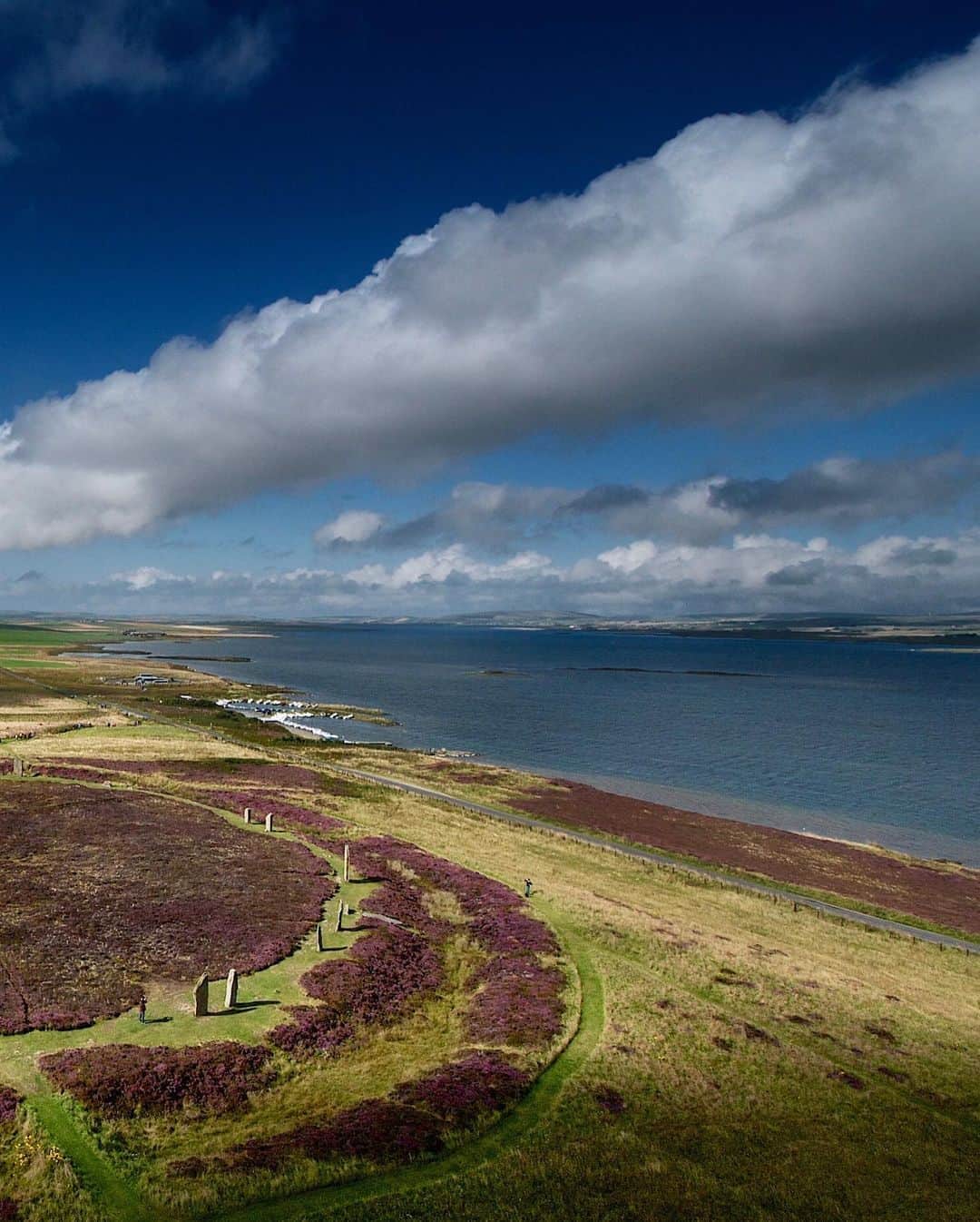 National Geographic Travelさんのインスタグラム写真 - (National Geographic TravelInstagram)「Photo by @jimrichardsonng / Covered with blooming heather, the Ring of Brodgar was enjoying a day in the sunshine as we sent our camera-carrying kite aloft in a stiff Orkney breeze. From this vantage point it was easy to see the henge, the raised earthen platform with a classic surrounding ditch cut deep into the underlying stone 5,000 years ago. The standing stones came later, added after the henge had already served as a focal point of the Orkney Neolithic community for some time. (On up the hill is another henge that never got any stones at all.) Brodgar sits on the narrow strip of land separating Lochs Stenness and Harray, making it a natural centerpiece of the surrounding farming community at the time. The Ring of Brodgar is just one of the cluster of Stone Age sites that make up the UNESCO World Heritage site called the Heart of Neolithic Orkney. (By the way, the kite was a bad idea.)  For more from Scotland, follow @JimRichardsonNG.」11月5日 0時20分 - natgeotravel