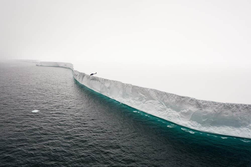 thephotosocietyさんのインスタグラム写真 - (thephotosocietyInstagram)「Photo by @nickcobbing  Scale was the first thing to hit me when I travelled to Antarctica for the very first time. Everything was bigger, icebergs and mountains towered above anything I’d known before. The tiny helicopter gives some scale to this iceberg which is approximately 11 miles long by five miles wide. I remembered it as being like an island with its own weather system. An island that would disappear slowly into the ocean.  The larger pieces of ice shelf that break off from the vast ice sheet covering Antarctica are given numerical names. They are catalogued. This one is named A57a and is a remnant of a larger iceberg that broke off the Larsen C Ice Shelf in 2008. So in that sense this iceberg is actually quite small.  #iceberg #Antarctica #adventure #expedition #scale」11月7日 7時24分 - thephotosociety