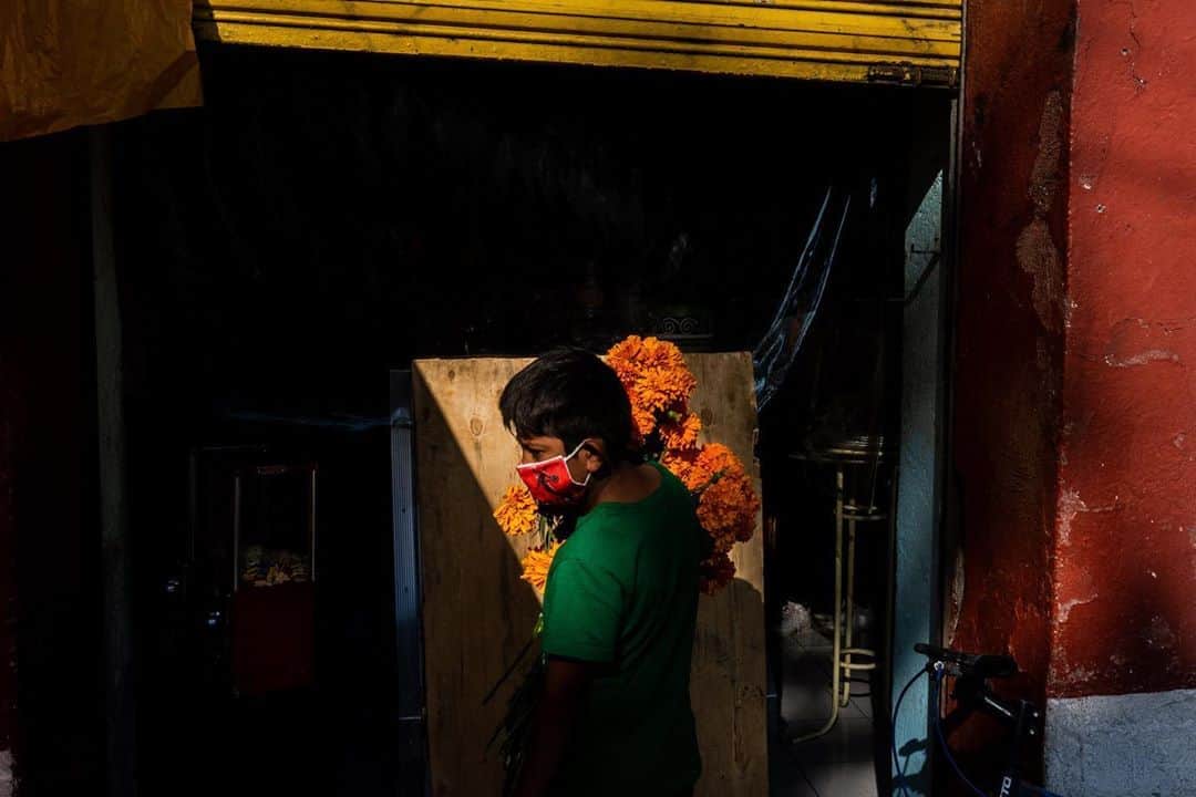 National Geographic Creativeさんのインスタグラム写真 - (National Geographic CreativeInstagram)「Photo by César Rodríguez @cesar_rodriguezb. / A young boy with a bouquet of marigolds waits for his mother outside a bakery as she buys offerings for Día de los Muertos, or the Day of the Dead, in San Andres Mixquic, Mexico. The yellow flower is strung over headstones and laid on altars, thought to represent the brightness of the sun illuminating a path for the spirits to return to Earth from Mictlán, the underworld. This year, the usually festive traditions around Dia de los Muertos were largely celebrated in private, but the souls of the dead aren’t just in cemeteries,  as Mexican Poet Jaime Sabines said “To die is to be everywhere in secret. Because with death you walk; we live with her since we are born.” Taken on assignment for @natgeo and @icrc」11月7日 9時14分 - natgeointhefield
