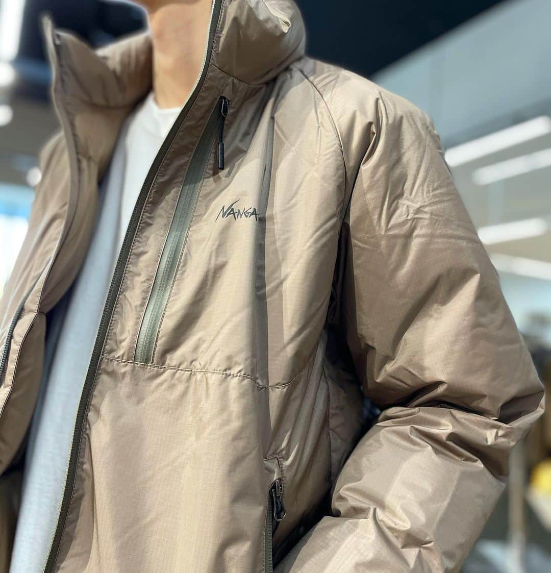のインスタグラム：「* 【NEW✨✨NANGA オーロラスタンドカラーダウンジャケット ！】 ＊ NANGAの中でも人気の ”オーロラダウJACKET” シリーズからスタンドカラーモデルが新しく仲間入り！  しかも定番TYPEからフードを外しリデザイン！  すっきりとした印象で よりスタイリッシュに、気軽に羽織れるジャケットに。  勿論フードジャケット付きも 入荷してます🙌 一一 NANGA独自開発ファブリックである“AURORA-TEX®”の機能は耐水圧20000mmで、雨などの侵入を防ぎます。  表面のステッチを可能な限り減らすことでステッチからの雨の侵入を最小限に抑えています。  またメインジップをはじめ、ポケット類のジップを全て止水ジップにすることで、防水性の向上はもちろん、デザインとしてもシャープなデザインに仕上がっています。  透湿性6000g/m²/24hrsは、ダウン内部からの湿気を外に逃がしてくれるので、軽い運動などをしても蒸れることが少なく、ドライで快適な着心地を維持します。  ジャケットの内側には柔らかな生地を採用することで、羽毛が膨らみやすくなり、着用時の保温性やフィットを高めます。  少し大きめなシルエットと、ラグランスリーブを採用することで、冬場の厚い衣服の上から着用しても窮屈さを感じさせません。  特徴的な両サイドの大きなポケットはハンドウォーマーとして手を素早く温めるだけではなく、グローブやアクセサリーなどの収納にも便利です。  ダウンの封入した立ち襟は冷気をしっかりと防いでくれるとともに、首元をしっかりと保温してくれます。  シンプルなデザインながらも高機能かつ使える仕様なのでアウトドアシーンではもちろんのこと、タウンでカジュアルに着用していただけるモデルになっています。  ■ブランド名：NANGA ■商品名：オーロラスタンドカラーダウンジャケット メンズ ■価格　¥37,000＋tax ■カラー：ブラック【N1asBK】,コヨーテ【N1asCY】,カーキ【N1asKH】 ■サイズ：S,M,L ■素材： 表生地／オーロラテックス® 裏生地／40dnナイロンタフタ 中綿／スパニッシュダックダウン 90-10% (760FP) ■羽毛量：120g ■重量／約586g ■生産国：日本 ・  SUNDAY MOUNTAIN ■THE GATE by SUNDAY MOUNTAIN  TEL 0776-97-8848 * 営業時間：11:00~19:00(水曜定休） ＝＝＝＝ * * #THEGATEbySUNDAYMOUNTAIN #sundaymountain #サンデーマウンテン #アウトドア #アウトドアショップ #アウトドアファッション #キャンプ #キャンプギア #ハイキング #福井  #パタゴニア　 #ノースフェイス #Xmas #ギフト #クリスマスプレゼント #アウトドア好き #nanga」