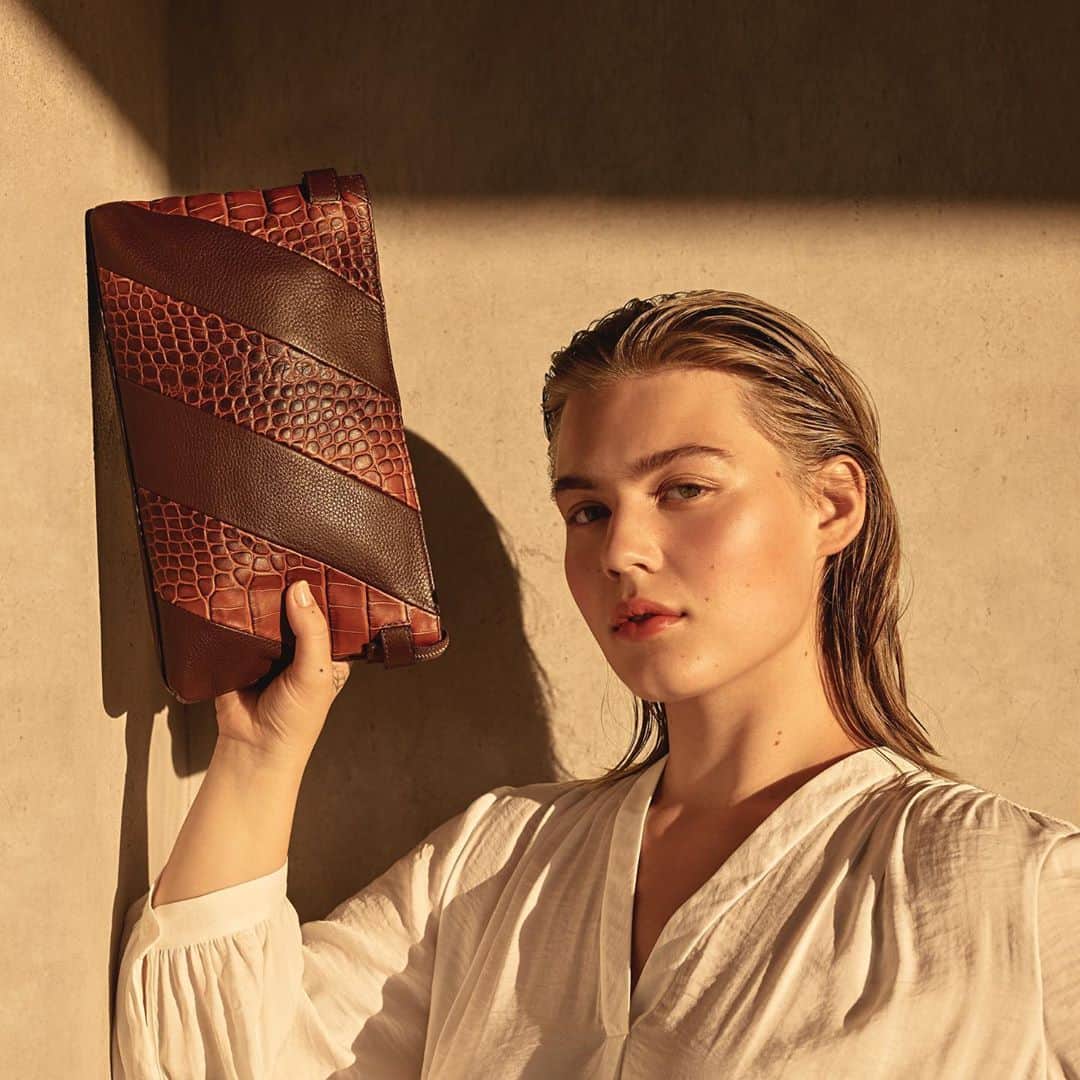 のインスタグラム：「Crafted in patchwork stripes of solid brown and reptile-embossed leather, we’re channeling the 70s with our convertible Casia Clutch. #vincecamuto」