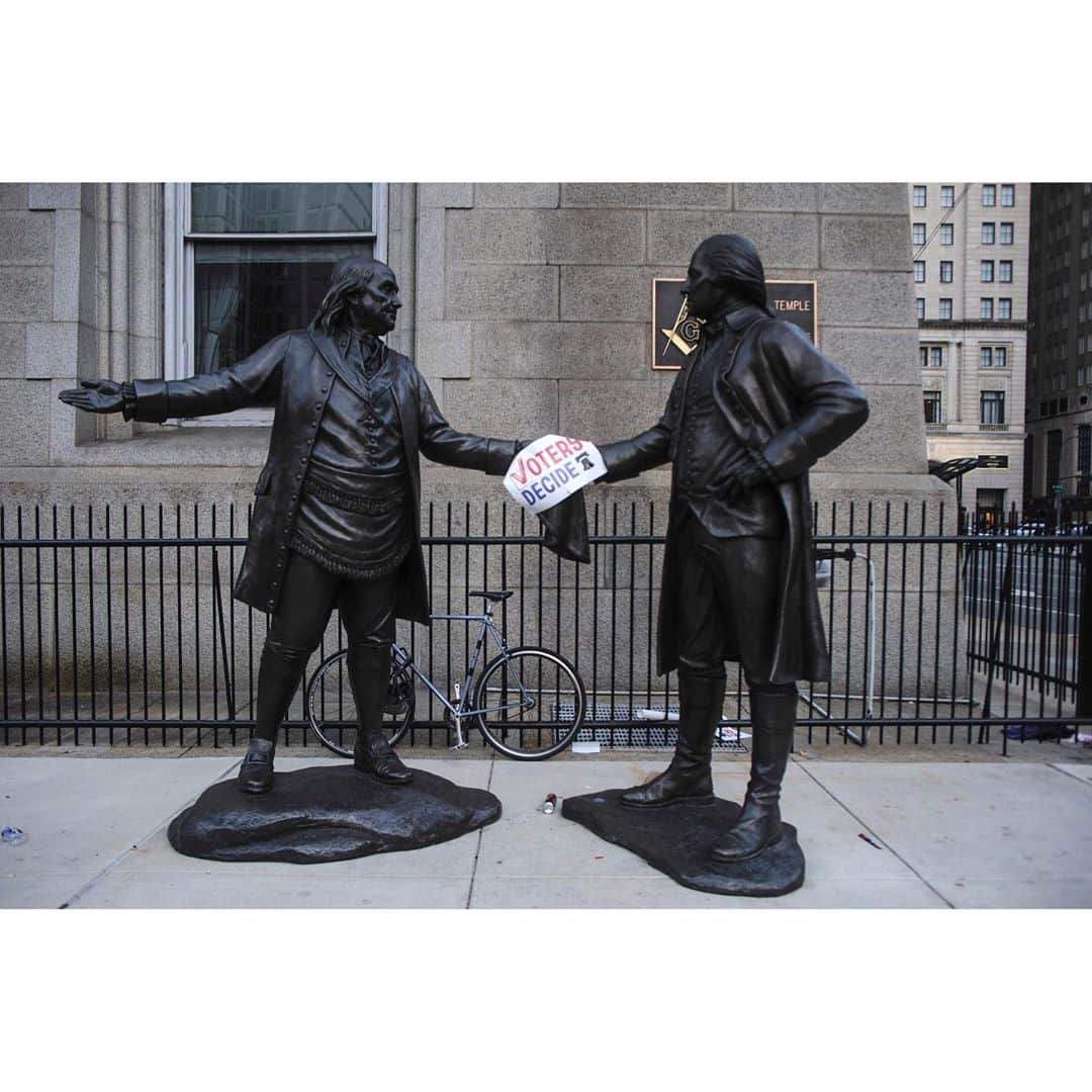 thephotosocietyさんのインスタグラム写真 - (thephotosocietyInstagram)「Photo by @stephenedwardferry  Philadelphia, PA.  On the day that the election was called for Joe Biden, someone placed a sign saying Voters Decide on a statue of George Washington and Benjamin Franklin greeting each other. Both sides in the deeply divided US look to historical motifs to anchor their message; indeed the first three words of the Constitution, “We The People…” can be seen tattooed both on the arms of Trump supporters and written on the signs of Biden backers. But what I like about this picture is the feeling of calm now that the election is over, and we will have an orderly transition of power without the threat of a violent constitutional crisis.  #vote #benjaminfranklin #georgewashington #election #philadelphia #reduxpictures #thephotosociety」11月10日 11時03分 - thephotosociety