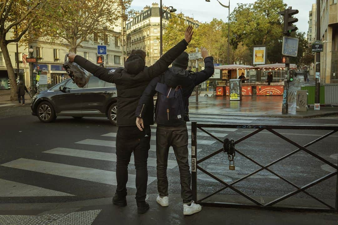 ルモンドさんのインスタグラム写真 - (ルモンドInstagram)「La rue de Belleville, à Paris, accueille paresseusement ses habitués du samedi matin. Au bar des Folies, les réguliers sont à peine perturbés par la transformation de l’institution du quartier en épicerie-pizzeria. « On est des caméléons. On regarde tous les jours ce qu’on a le droit de faire, et on s’adapte », s’amuse presque le serveur. Ce n’est pas pour déplaire à Khalil Ghabara, qui continue à venir tous les matins, « comme avant ». Il sort plusieurs fois par jour, usant d’une attestation puis d’une autre. « Mais toujours en règle ! »⁣ Les stores baissés se font de plus en plus rares en remontant la rue, et les trottoirs se gorgent de badauds. Un couple s’arrête devant une papeterie, ouverte elle aussi. « Dis, chéri, on ne rentrerait pas là ? On n’y est jamais allés ! » Boulanger, boucher, poissonnier, fromager… Les files s’étirent, moins longues que lors du premier confinement mais pleines toute la journée. « Est-ce que c’est très raisonnable ? Je ne sais pas », convient Sabine Civilise en attendant son tour – « J’avais envie de lapin ! » – à la boucherie.⁣ La boutique vide et l’air contrarié, Mahnaz la chocolatière observe la rue débordant de vie en soupirant. « Les gens sont des enfants, les policiers sont occupés ailleurs, alors, ils en profitent pour passer entre les gouttes… » En Iran, Mahnaz a connu la guerre, puis l’embargo. « Du coup quand les gens disent : “J’en ai marre d’être confiné”, alors que les rayons des magasins sont pleins, je préfère ne rien dire… » Sans en penser moins.⁣ -⁣ 1 : Le café des Folies s’est reconverti momentanément en pizzeria-traiteur pour contourner les mesures de fermeture⁣ 2 : Foued, peintre, boit un café rue de Belleville, le 7 novembre⁣ 3 : Les files d’attentes devant les commerces de bouche de la rue de Belleville⁣ 4 : Davy et Stéphane, après avoir fait la fête toute la nuit chez des amis, sont à la recherche d’huîtres et de vin blanc sur le marché⁣ 5 : Mahnaz, dans sa boutique de chocolats⁣ 6 : Sophie et Brigitte partagent leur café du matin devant l’église de Belleville⁣ 7 : La rue de Belleville à Paris le 7 novembre⁣ -⁣ Photos : Agnès Dherbeys (@agnes_dherbeys) #PourLeMonde⁣ -⁣ #covid #coronavirus #commerce」11月11日 22時42分 - lemondefr