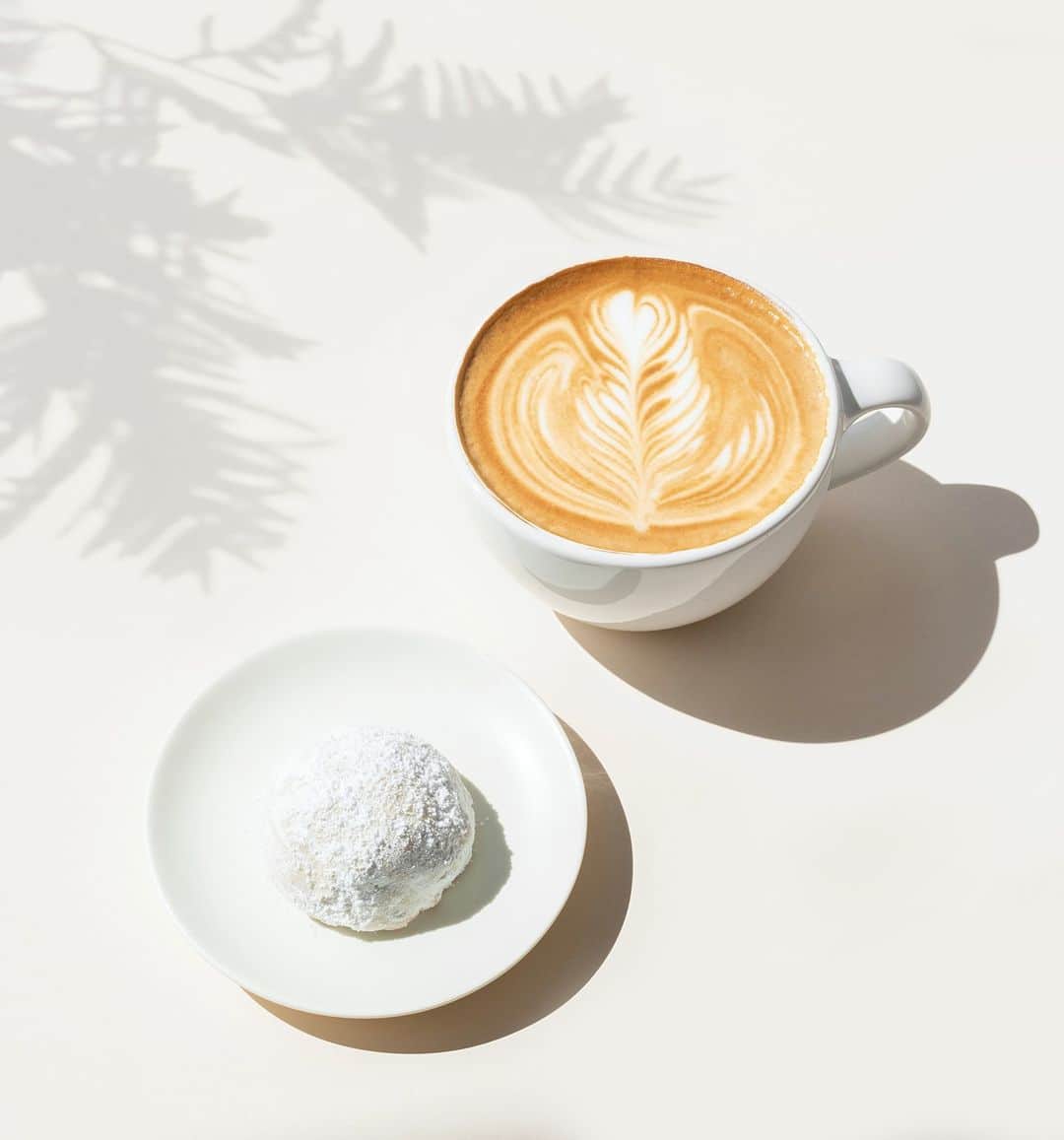 Blue Bottle Coffeeのインスタグラム：「Our holiday menu celebrates the season’s promise of renewal. Our playful latte sweetened with the honey of acacia blossoms brings out the sweet nuttiness of our almond cardamom snowball cookie. For even more winter treats, use our link in bio to download our app to view the full seasonal menu.」