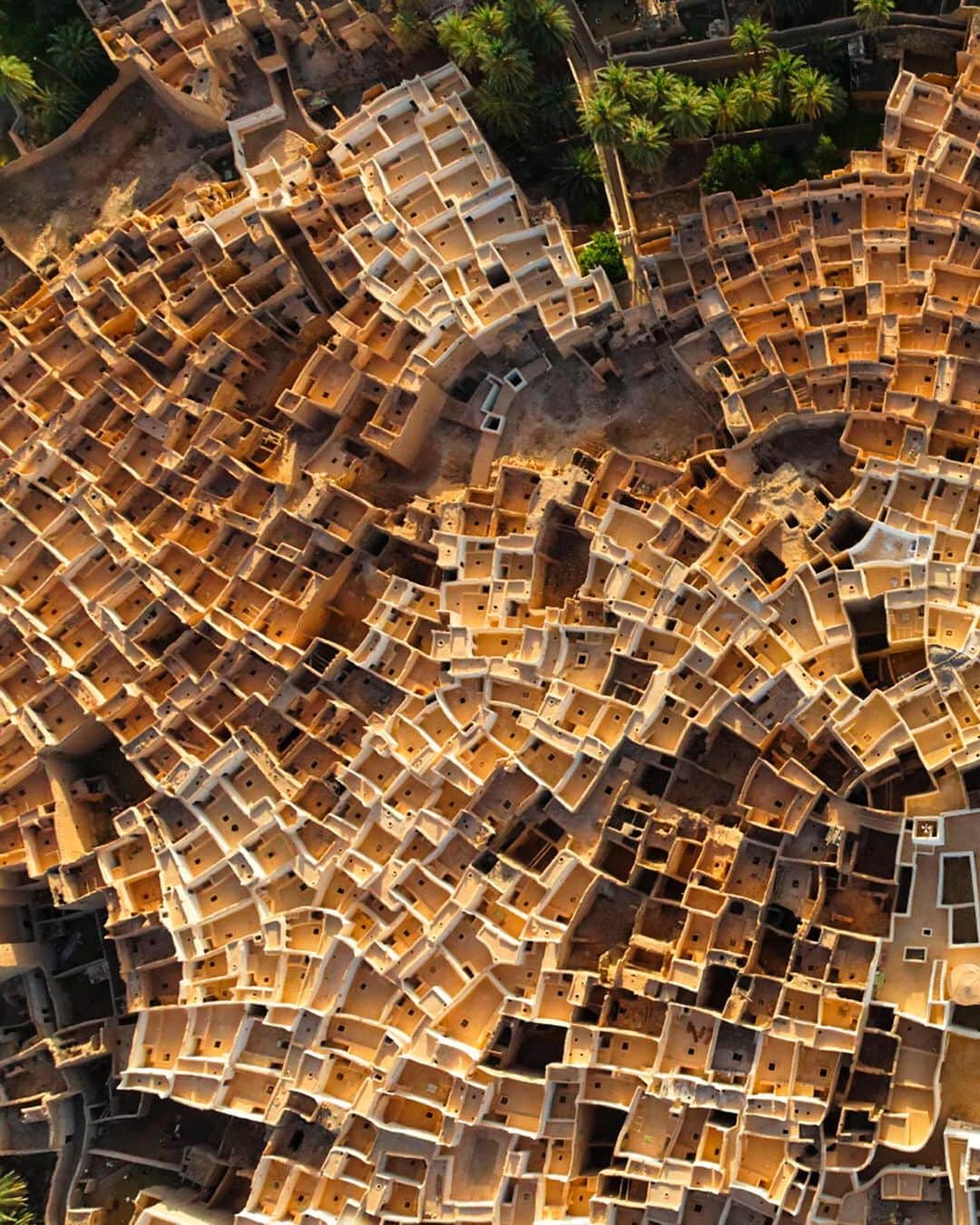 National Geographic Travelさんのインスタグラム写真 - (National Geographic TravelInstagram)「Photo by George Steinmetz @geosteinmetz / The venerable homes of the old walled city of Ghadames, Libya, honeycomb a pre-Saharan oasis on the desert’s edge. The thick albescent walls reflect the sunlight and keep the interiors of these buildings cool in all but the hottest summer months. The flat roofs are designed as warm weather sleeping areas and are connected to one another by pathways, just as a network of ground-level alleys provides covered walkways protected from the sun. The city, which has no electricity or plumbing, was abandoned in the early 1980s when the government built new housing for the residents. Many continue to maintain their ancestral homes, however, and the city has become a popular tourist destination, a paradigm of sustainable architecture from which the world has much to learn.  To explore more of our world from above, follow @geosteinmetz. #UNESCOWorldHeritage」11月18日 4時38分 - natgeotravel