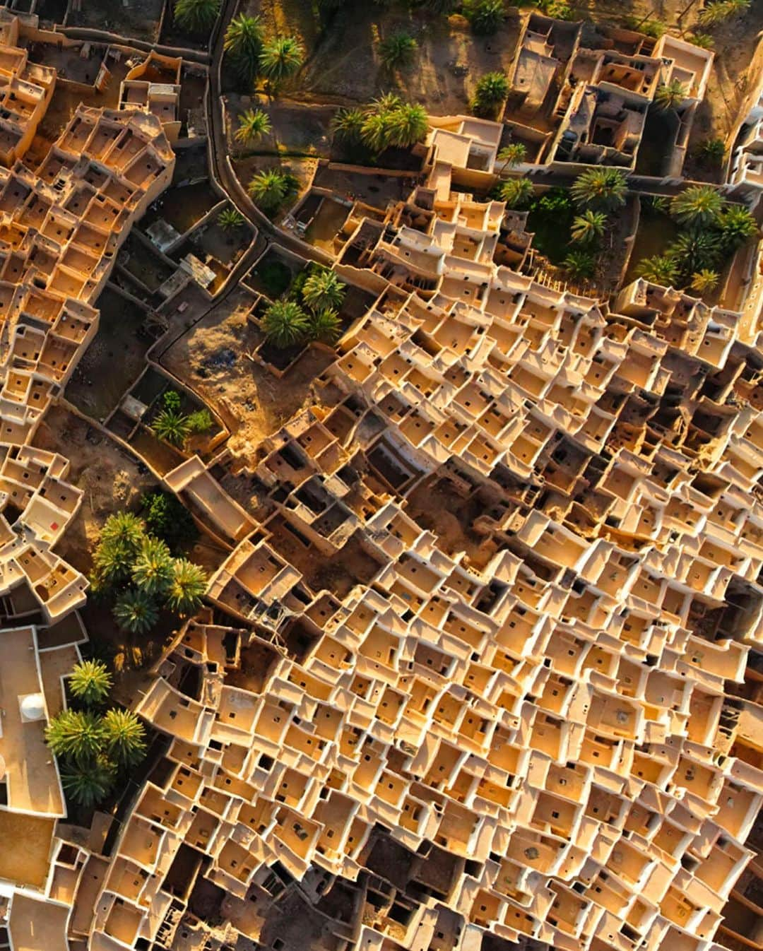 National Geographic Travelさんのインスタグラム写真 - (National Geographic TravelInstagram)「Photo by George Steinmetz @geosteinmetz / The venerable homes of the old walled city of Ghadames, Libya, honeycomb a pre-Saharan oasis on the desert’s edge. The thick albescent walls reflect the sunlight and keep the interiors of these buildings cool in all but the hottest summer months. The flat roofs are designed as warm weather sleeping areas and are connected to one another by pathways, just as a network of ground-level alleys provides covered walkways protected from the sun. The city, which has no electricity or plumbing, was abandoned in the early 1980s when the government built new housing for the residents. Many continue to maintain their ancestral homes, however, and the city has become a popular tourist destination, a paradigm of sustainable architecture from which the world has much to learn.  To explore more of our world from above, follow @geosteinmetz. #UNESCOWorldHeritage」11月18日 4時38分 - natgeotravel