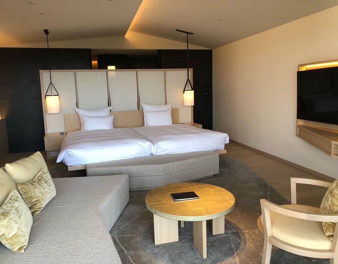 進藤やす子のインスタグラム：「✳︎ （SORANO HOTELの投稿ラストです🤗） 客室はスタンダードでも52㎡というゆったりとした作りで、しかも全室パークビューで眺望が抜けているので、より広く感じます。 . そして面白いのが、客室への通路や客室内の色んなところが直線ではなく"角度がついてる"んですが、デザイナーのニコラ氏が「自然界に直線は無いから」というこだわりなんだとか。 . また、ひとつ目の投稿にも書いた"三角屋根⛺️"が客室にもあるのも可愛い！写真1枚目、手前のソファとベッド前のオットマンをパズルのように合わせるとベッドに早変わりしたり、色々楽しい仕掛けが。 . 3、4枚目は黒い畳バージョンの客室。４人まで宿泊可能で、布団を敷くと4枚目のようになり、わいわい女子会してる様子が目に浮かびます😁 . 10階のジムから見える昭和記念公園の紅葉が綺麗🍁 最後の2枚はロビー奥のちょっとしたサロンスペース。 ほんとどこを切り取ってもこだわりたっぷり✨ . アメニティは最小限、歯ブラシは自分で持ってきてねというスタンスも今っぽくて好感が持てました。 . ちなみに、愛犬と一緒に泊まれる客室は大人気で、週末だけでなく平日もだいぶ先まで埋まっているそう。 . 予想以上に素晴らしかったSORANO HOTEL、さっそくリピーターが結構いるというのも納得でした〜✨ . . #soranohotel @soranohotel  #ソラノホテル #GREENSPRINGS  #立川 #全室パークビュー」