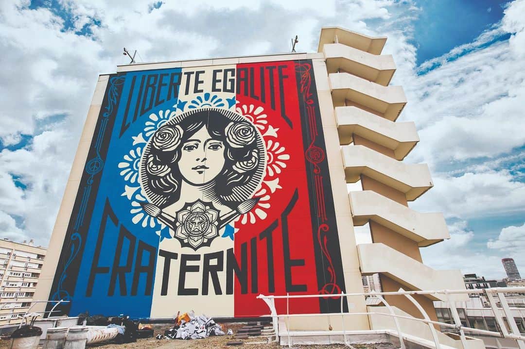 Shepard Faireyのインスタグラム：「Traveling for gallery openings and murals is something I'm really missing this year. This week, I'm throwing it back to a very memorable trip to Paris in 2016. After my "Earth Crisis" installation at the Eiffel Tower during the COP 21 in 2015, Galerie Itinerrance and I planned a follow-up art show and murals to build on the concept and aesthetics of the "Earth Crisis" installation. I worked hard creating new pieces of environmentally-themed art and new versions of some older works in the aqua and blue colorway that I used for the Earth Crisis globe.⁠⠀ ⁠⠀ The weather forecast called for rain basically every day for the duration of the trip, but my team and I were able to catch some dry windows to jump on the murals. I realized that all the hours the crew and I have been putting into walls have made us faster, and we finished everything on time, even with the rain delays. I was incredibly moved by the Parisians' response who gathered daily, rain, or shine, to watch us work on the murals. When we finished the "Delicate Balance" mural, the assembled crowd cheered and clapped for a couple of minutes. I'm used to being chased, yelled at, questioned, and sometimes arrested for doing public art, so to be cheered was pretty emotional.⁠⠀ ⁠⠀ I remember feeling so grateful to so many Parisians for their enthusiastic support of my work. Many of the French I encountered apologized for not speaking English well, and I was a bit ashamed that I'm not multilingual. Regardless, I think the art spoke a universal language that communicated the idea that we are one people on one planet! Let's not forget that whatever language we speak or whatever country we reside in, we are in this all together.⁠⠀ -Shepard  Photos by @jonathanfurlong」