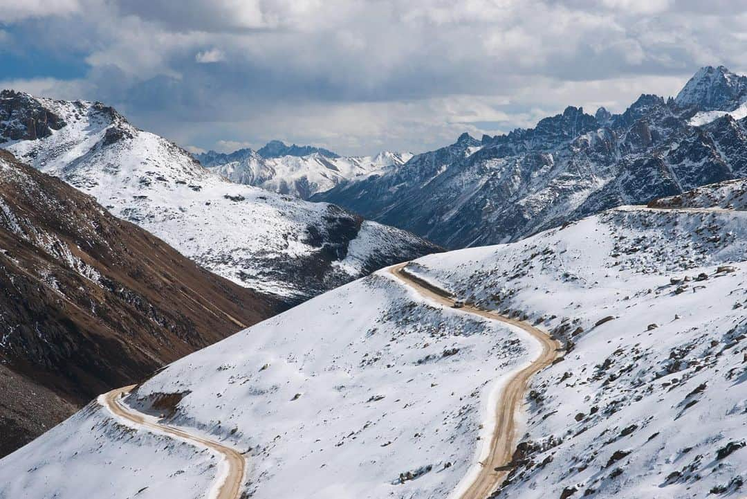 Michael Yamashitaさんのインスタグラム写真 - (Michael YamashitaInstagram)「Long and winding road: Mountain passes like these in Kham (eastern Tibet) offer some of the most spectacular vantage points for photography, but sadly, they are disappearing as China burrows under the ranges with tunnels to make way for highways. Though the tunnels decrease travel time and make the far reaches of Tibet more accessible, they now make it harder than ever to reach these passes. In the past, I would look forward to driving over these sometimes treacherous lofty passes by four-wheel drive to take advantage of the panoramic picture possibilities from the top.  Now the only way over is by foot, not an easy feat when hiking over mountains at altitudes as high as 15,000 feet.   From the new edition of my book, SHANGRI-LA [ALONG THE TEA ROAD TO LHASA]. Available where books are sold.  #ShangriLa #teahorseroad #tibet #newbookalert #Yunnan #mountainpass」12月16日 4時38分 - yamashitaphoto