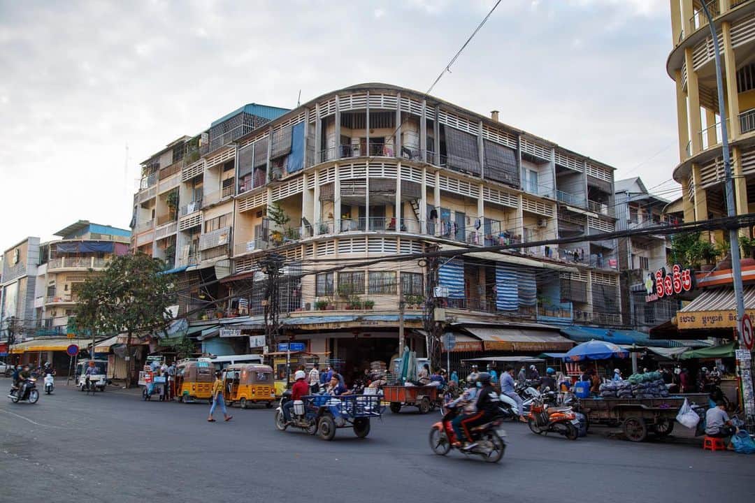 Shunsuke Miyatakeのインスタグラム：「This is a corner of St.182 and St.141 in front of Orussey Market.  Motos, motos with a cargo people sitting with loads, TukTuk, auto rickshaw, and classic buildings in the morning light at 0646am.  There's an Everyday Life on every corner of Phnom Penh.」