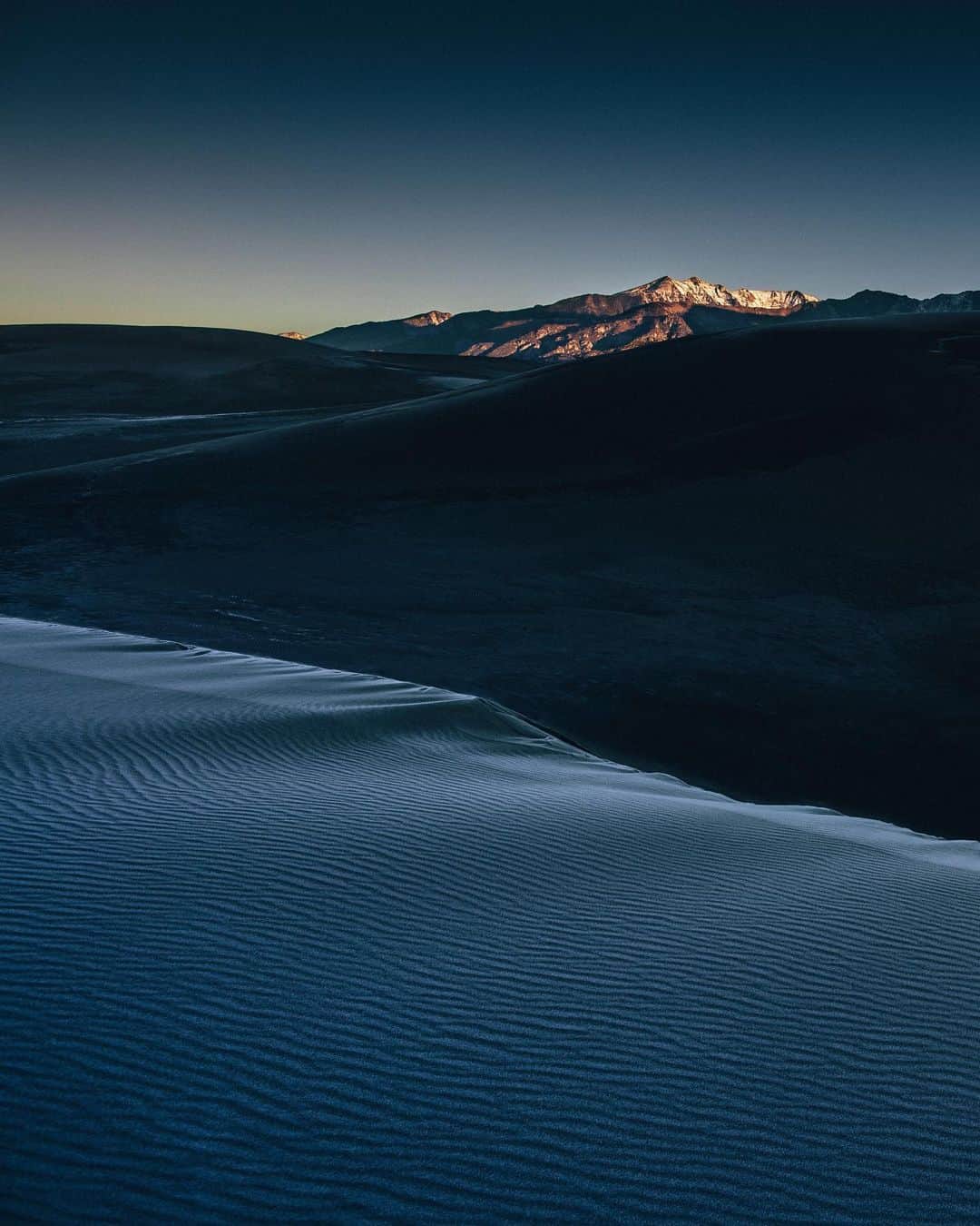 National Geographic Travelさんのインスタグラム写真 - (National Geographic TravelInstagram)「Photo by @joshuacogan / Trying to catch sunrise at Great Sand Dunes National Park can be a challenge. Getting up onto the dunes themselves is no easy task, as every step equals two on a normal ascent because the sand gives no solid surface. On this frosty early morning, I was rewarded with a few nice surprises: the cresting sun on the snowcapped peaks in the background and the frost-covered dunes in the foreground creating beautiful glistening reflections.  For more images of our incredible public lands and journeys through the world, follow me @joshuacogan. #ourpubliclands」11月28日 1時35分 - natgeotravel