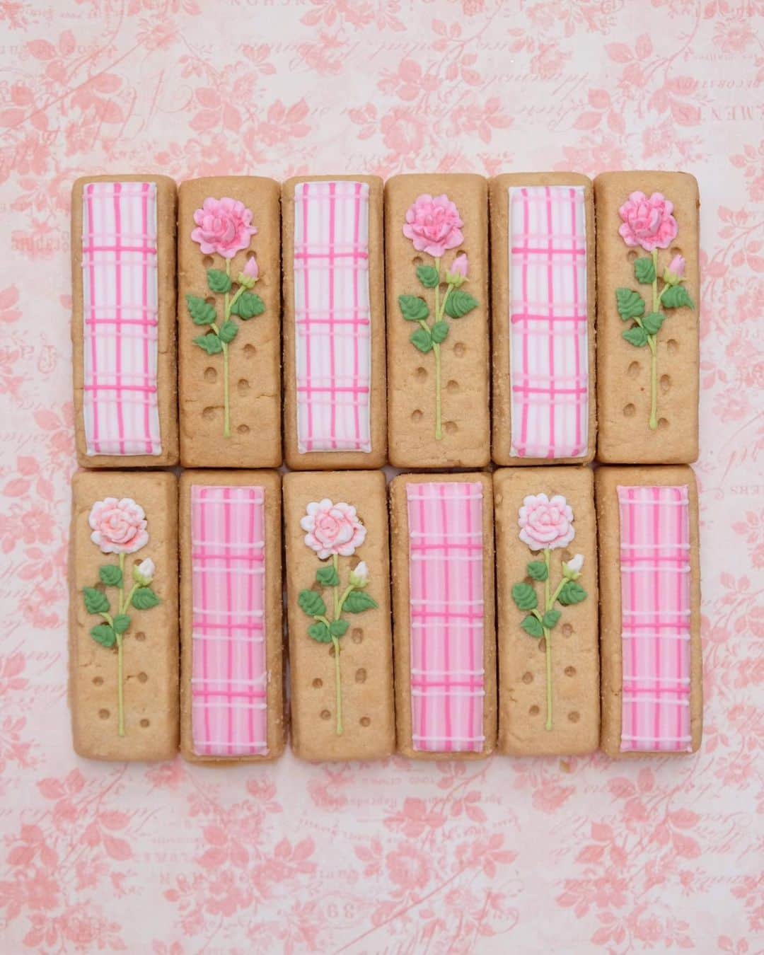 KUNIKAのインスタグラム：「I decorated lovely pink rose and check pattern on the @walkersshortbread 🌹 It's first time to put icing on the shortbread, these are good treats for tea time!  先日のインスタライブでデコレーションしたWalkersのショートブレッド🌹 縦長の形を活かしたチェック柄と、ショートブレッドの穴をそのまま活かした薔薇の絞りデザインをやりました。  本当はこれでひとつのレッスンできるのかもしれないけど、今は皆さまにアイシングクッキーが出来上がっていく過程を楽しんでもらえたり、創作のヒントになったら嬉しくて、ゆるくインスタライブしています😇 いつもコメントありがとうございます🤍  #artofkunika」