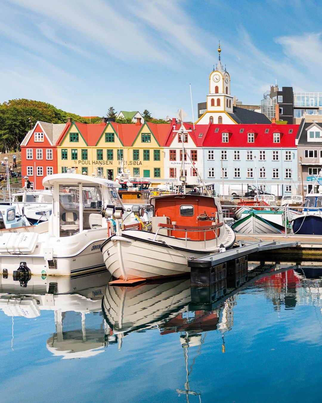 Lonely Planetのインスタグラム：「“Many people are familiar with the dramatic landscapes of the Faroe Islands, so as a counterpoint I wanted to photograph the delightful capital city of Tórshavn. I had a couple of hours spare so I went exploring. I was able to walk freely around parliament and the government buildings; everything was open and there was no visible security. I then stumbled upon the harbor area. It was an incredibly calm afternoon so there were perfect reflections on the water. I walked down a number of pontoons, but the boats were blocking my view. I eventually found one with a large gap in the moorings, allowing me a clear view back towards the colorful old buildings, with fishing boats moored in the foreground. I think the primary colors of the buildings, with the blue sky above (and reflected below), is what makes this image stand out so well.”  -Photographer Justin Foulkes  Tap the link in our bio to see this book.」