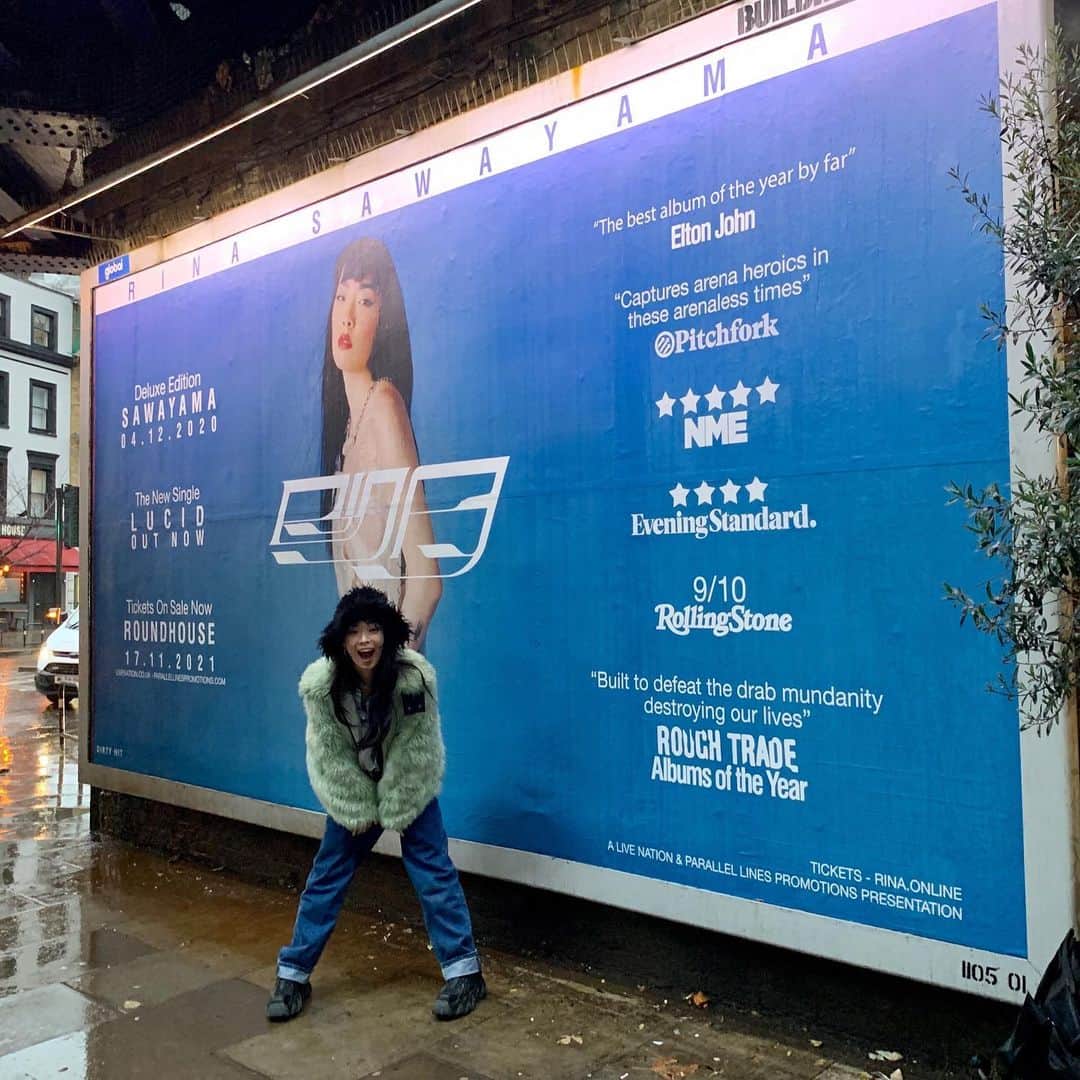 リナ・サワヤマのインスタグラム：「SO MANY THINGS HAPPENING TODAY 🥺  1) DELUXE SAWAYAMA IS OUT !!! stream/download the 11 track Disc 2 in my bio !!!!   2) GENERAL TICKETS FOR UK + IRELAND 2021 SHOWS ON SALE !!  3) LUCID video premiere tonight at 6pm GMT ! Then right afterwards is the premiere for the Behind the scenes video !!!!! PREMIERE ROOM NOW OPEN !! see u in the chat maybe 😏  4) here I am in front of my first UK billboard in a characteristically rainy af day under Camden road station !!!!! take a pic in front and tag me !!!」