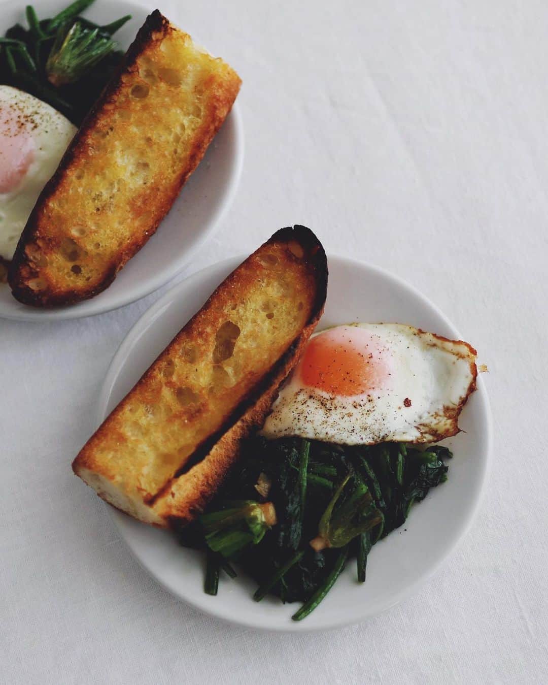 のインスタグラム：「Today's breakfast . 朝ごはんは目玉焼きと、 トーストしてバターを よーく塗ったバゲット、 ホウレンソウのソテー。 . ホウレンソウの根本が 好きなの少数派かしら。 . . #朝食 #朝ごはん #普段の朝食 #目玉焼き #バゲット #ほうれん草のソテー #breakfast」