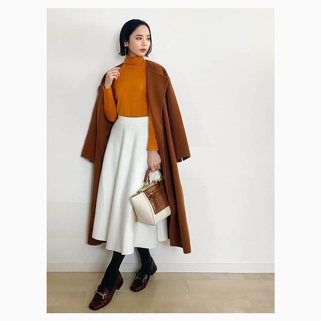 のインスタグラム：「冬の真っ白スカートで通勤! 🫖🍩♡ オフ白ならあいまい配色, 真っ白ならコントラスト配色がよく合うと思います。 今回は オレンジっぽいニットにキャメルの コントラスト配色🍊🧶🧡 スカートはぎゅっと目の詰まった 滑らかなニット地で, ぱっと見ニットとわからなさそう。形がすごく綺麗で 穿いていてめちゃめちゃテンションが上がりました😭  黒ニットやパールと モノトーンで合わせたり, ネイビー×赤のボーダーで冬マリンにしたり……と 想像が膨らむ🤤 着まわすのが楽しみです!  knit. #zara skirt. @lialapg  coat. #spickandspan  tights. #blondoll 17℃ (ダークセピア 30デニール) loafer. @dianashoespress  bag. #zanchetti choker. @noirdepoupee_official  pierce. #mikimoto @hirotakajewelry  earcuff. #hirotakajewelry #hirotaka  ring. #cuicui #noirdepoupee  watch. #agete  #お仕事コーデ #オフィスカジュアル #オフィスコーデ #お仕事服 #通勤コーデ #通勤スタイル #olコーデ #テレワークコーデ #在宅勤務コーデ  #オレンジニット #ザラ購入品 #ザラ #白スカート #ニットスカート #lialapg pr #ガウンコート #キャメルコート #ローファー」