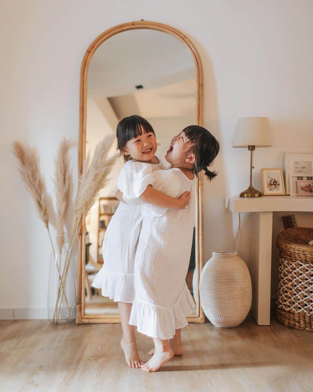 MOMOツインズのインスタグラム：「Both of you have so much love to give to those around you. You are always so generous in your hugs and kisses and often tell the people you are close to how much you appreciate them. When i am upset, you kiss my cheek and tell me everything is ok. You always manage to find happiness in the smallest of things and your positivity lights up the room. I love how you feel so deeply and are not afraid to express your emotions. You are an absolute joy to be around with, Leia and Lauren ❤️  #momotwins #blessed  Standing rattan mirror from @rooma_sg  Dresses from @sonanddaughter.co Vinyl flooring @thewoodflooring」