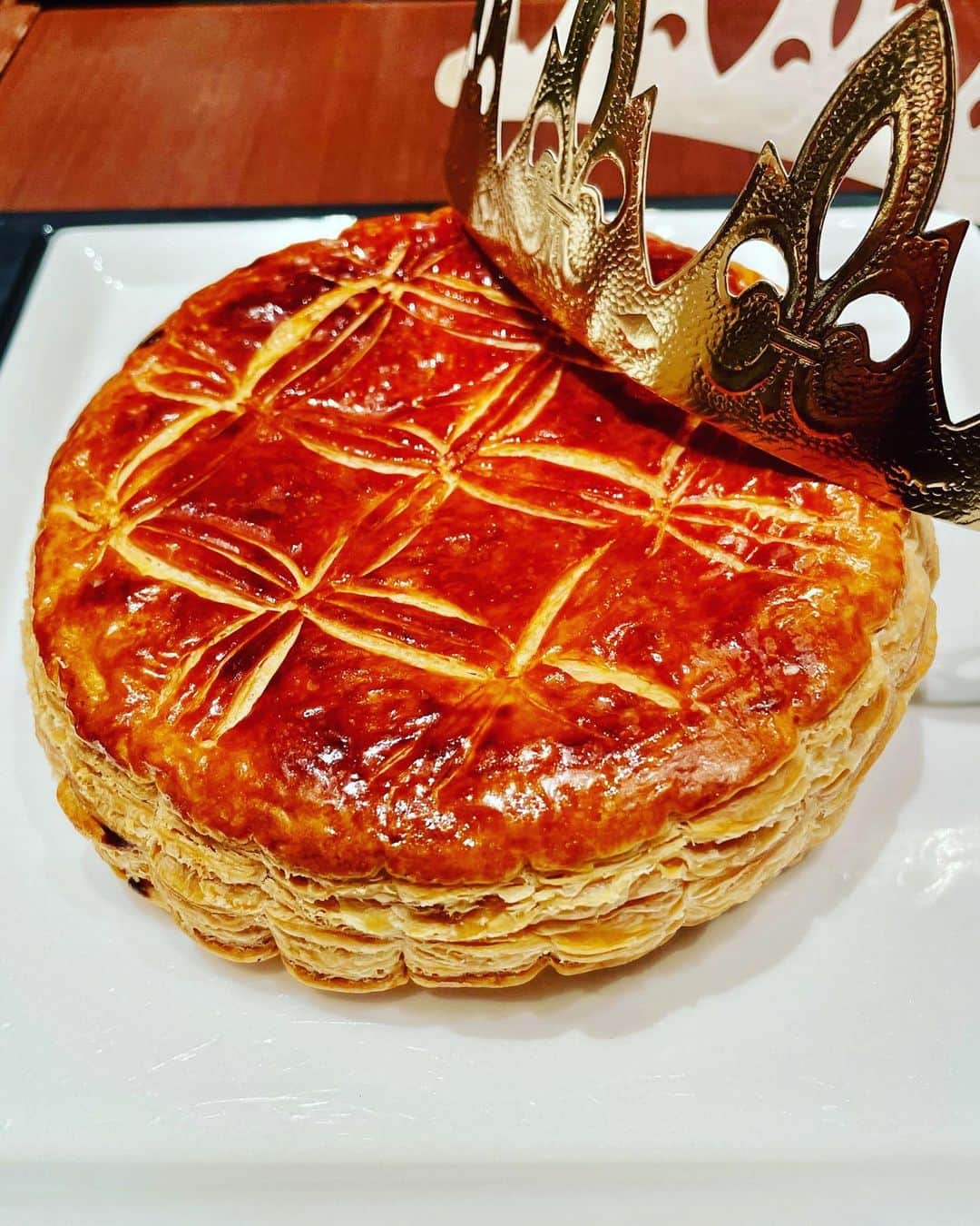 永吉明日香のインスタグラム：「新年を祝う、フランス伝統の #ガレットデロワ を初めて味わいました🥮❤️ サクサクのパイ生地とアーモンドクリームのお菓子で、めちゃくちゃおいしかったーーー😋 仕込まれた陶器製の"フェーブ"が、食べたガレットデロワの中から出てきた人が、王冠をかぶる👑っていう楽しみ方☺️ フェーブが当たったので、王冠かぶって食べ続けました笑 こんなに楽しい伝統、日本にも広まればいいのに〜！！！ 楽しいおいしい時間でした☕️🥮 #目つぶっちゃった写真載せとくね#口元にお菓子ついてるし🤨」