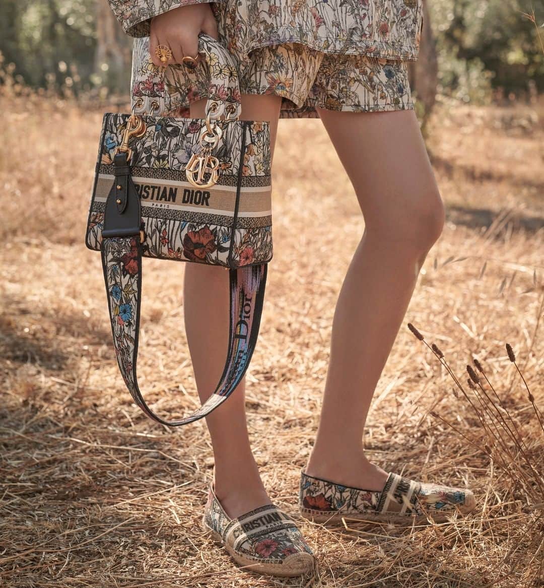 のインスタグラム：「In the dappled shade of a Puglian olive grove, the characteristic 'Mille Fleurs' motifs by @PietroRuffoArtist in the #DiorCruise 2021 collection by @MariaGraziaChiuri bloom across such key pieces as the embroidered #LadyDLite bag with matching strap, 'Dior Granville' espadrilles, and the airy techno taffeta jacquard anorak accessorized with a scarf softly tied around the hair. Tap the link in bio for more. © Photos: @SarahBlais」