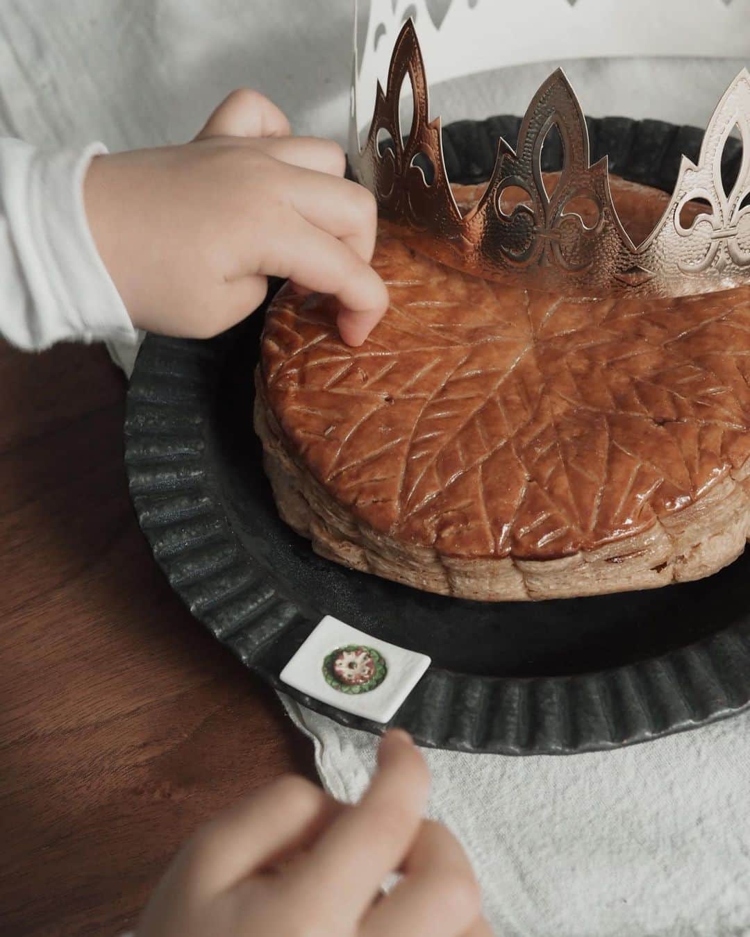 のインスタグラム：「Our first galette des rois﻿👑 ﻿ ﻿ ﻿ 初のガレットデロア ﻿ この時期あちこちのお店で見かけるので﻿ 今年から新年祝いに買ってみようかと 手始めにジョエル・ロブションのものを🥧﻿ ﻿ フェーヴは別添でフェーヴ代わりのアーモンドは﻿ 真っ二つに割れてじーちゃんとばーちゃんのもとへ﻿ ﻿ 王冠はフェーヴに関係なくちょうどエルサのティアラが壊れて落ち込んでいたMiaのもとへ🧒🏻﻿  タイミングバッチリ😁✨ ﻿ ﻿ ﻿ ﻿ #galettedesrois #ガレットデロア #joelrobuchon  #生後7ヶ月 #7mnthsold #おかっぱ赤ちゃん #5月28日生まれ #えくぼちゃん #ハーフベビー #令和ベビー #35monthsold #2y11m #2歳11ヶ月 #たれ目 #たれ眉 #miababyliving」