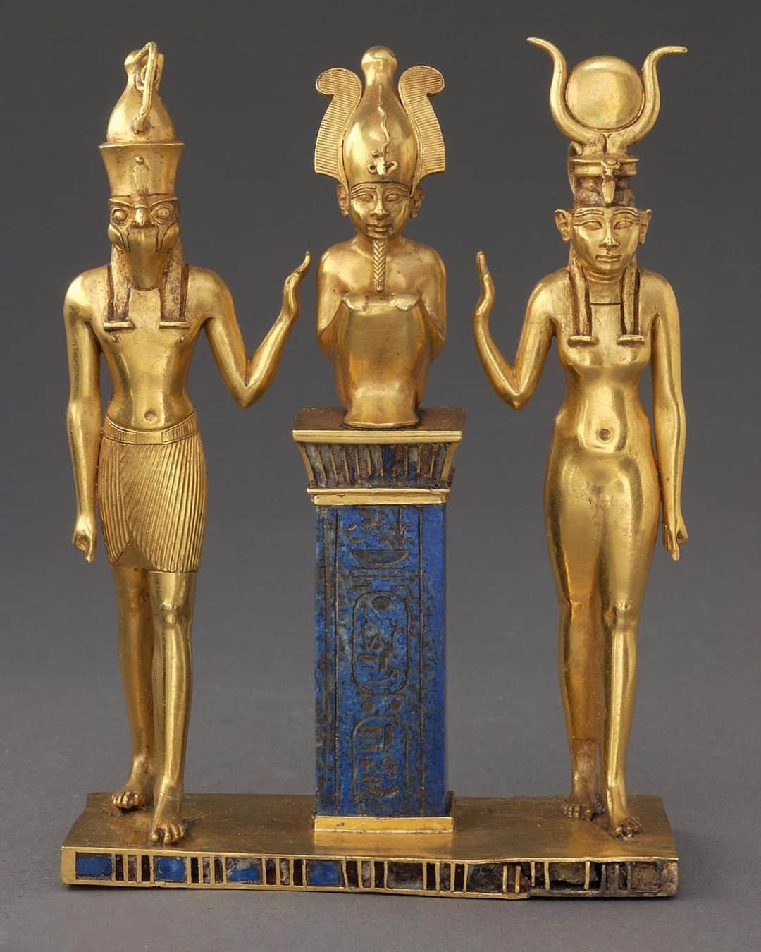 ルーブル美術館のインスタグラム：「. 🇫🇷 La famille du Dieu Osiris vous souhaite une bonne semaine ! 🙂 - 🔎 Ce bijou extrêmement précieux en or plein et en lapis-lazuli, authentique chef-d’œuvre de l'orfèvrerie antique, représente la triade divine de la famille d'Osiris. Trois figurines en or plein représentent Osiris entouré par son fils Horus et son épouse Isis, levant la main en un geste protecteur. - 🦅 On les reconnaît à leurs attributs : tiare à plumes et suaire pour Osiris, tête de faucon et double couronne royale pour Horus, disque encadré de cornes de vache pour Isis, à l'imitation de la déesse Hathor. Osiris est accroupi sur un pilier en lapis-lazuli d'un bleu intense qui le rehausse au niveau des membres de sa famille. Les palmes de la corniche ainsi que le socle sont travaillés en cloisonné d'or, incrusté de lapis et de verre rouge. - ✨ Ce bijou semble être un trésor de temple, un attribut de quelque haute fonction religieuse. A l'arrière, des bélières permettaient de le suspendre comme un pectoral. - - - - 🌎 The God Osiris's Family wishes you a good week! 🙂 - 🔎 This extremely precious solid gold and lapis lazuli item of jewelry - a true masterpiece of antique goldwork - represents the holy triad of the Osiris family. The three solid gold figures represent Osiris, surrounded by his son, Horus, and his wife, Isis, extending their hands in a protective gesture. - 🦅 These gods are recognizable by their attributes: the feathered tiara and shroud for Osiris; the falcon head and double royal crown for Horus; and the horned disk for Isis, in imitation of the goddess Hathor. Osiris is crouching on a pillar of a deep blue lapis lazuli that places him at the same level as his family. The palm leaves on the cornice and the base are fashioned in gold cloisonné inlaid with lapis and red glass. - ✨ This piece of jewelry seems to be a temple treasure - an attribute that played a considerable religious role. Rings on the back could have been used to hang the object like a breastplate. - 📷 © Musée du Louvre, dist. RMN - Grand Palais / Christian Décamps . . . #Louvre #MuséeDuLouvre #LouvreChezVous #MuseumFromHome #CultureChezNous」