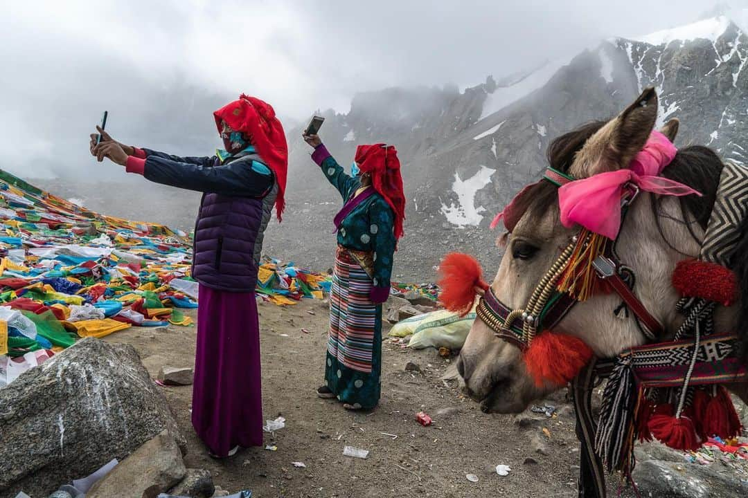 thephotosocietyさんのインスタグラム写真 - (thephotosocietyInstagram)「Photo by Brendan Hoffman @hoffmanbrendan // Buddhist pilgrims wearing masks against the sun and dust take celebratory selfies at the Drolma La, which at 5630 meters, or nearly 18,500 feet, is the highest point on the kora around Mount Kailash, in far western Tibet. I made this picture in 2019 on assignment for a National Geographic Magazine story about the Indus River. The four faces of the pyramid-like Mt. Kailash symbolize the four major rivers that originate nearby, with the north face representing the Indus. Also known as Kangrinboqe, the peak is sacred to four religions. Hindus, Buddhists, Jains, and Bönpo all make pilgrimages around its base, though the mountain itself has never been climbed. The kora is a circumambulation of the mountain, clockwise for all but Bönpo, on a path that covers 56 kilometers, or 35 miles. Follow me @hoffmanbrendan for more human stories from around the world. @natgeo #mountkailash #tibet #china」1月12日 3時06分 - thephotosociety