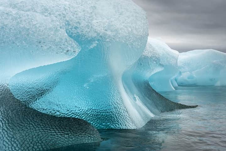 National Geographic Travelさんのインスタグラム写真 - (National Geographic TravelInstagram)「Photo by @daisygilardini / We experienced unusual weather during my last expedition to Antarctica this past January. We had gloomy, overcast, and rainy weather for the whole month, with only three or four partly sunny days. I really dislike shooting in rain, but I have to admit that I enjoyed some of the stormy cloud formations we witnessed—even though, by the end, I was desperate for some warm sunset and sunrise colors. Iceberg photography is actually better under an overcast sky, as the clouds act as a huge diffuser filter. That dramatically reduces the dynamic range in the image because it eliminates strong shadows and bright highlights and enhances the blues of the ice at the same time.  Follow me @daisygilardini for more images and behind-the-scenes stories. #conservation #climatechange #iceberg #storm #antarctica」1月12日 8時36分 - natgeotravel