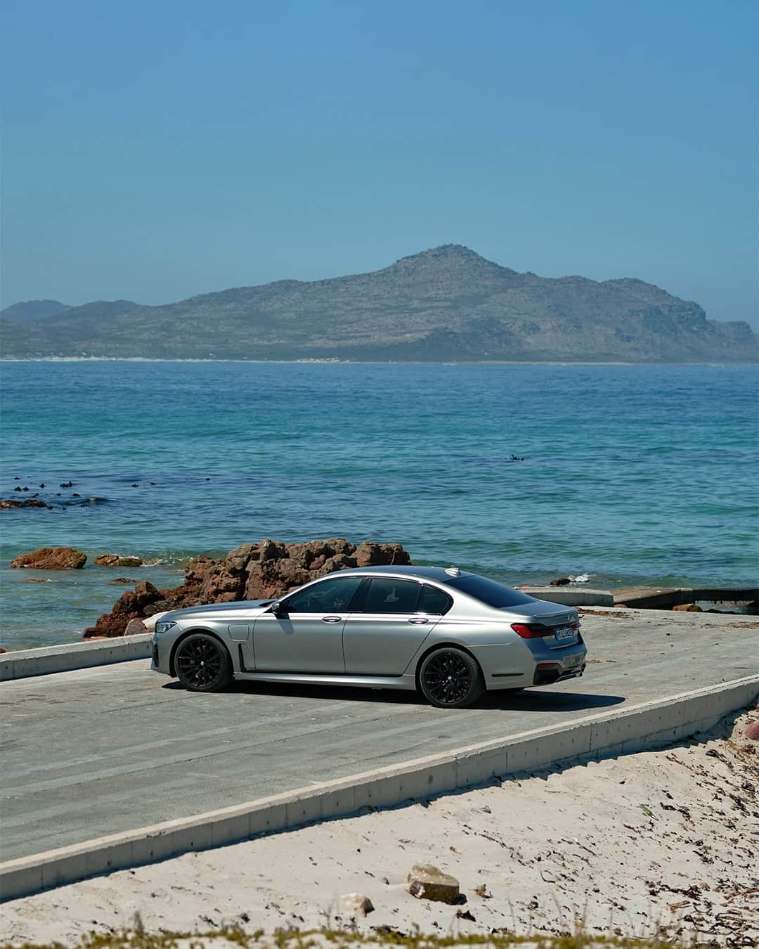 BMWのインスタグラム：「The shiniest pebble of the beach. The BMW 7 Series Sedan. #THE7 #BMW #7Series #pluginhybrid #joyelectrified __ BMW 745e Sedan: Fuel consumption weighted combined in l/100km: 2.2–2.1 (NEDC); 2.2–1.8 (WLTP), CO2 emissions weighted combined in g/km: 50–49 (NEDC); 49–41 (WLTP), Power consumption weighted combined in kWh/100km: 16.6–16.3 (NEDC); 19.0–17.7 (WLTP). Further information: www.bmw.com/disclaimer   394 hp, 290 kW, 600 Nm, Acceleration (0-100 km/h): 5.2 s, Top speed (limited): 250 km/h.」