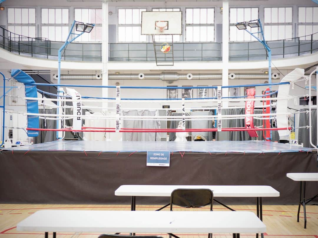 ルモンドさんのインスタグラム写真 - (ルモンドInstagram)「Dans la salle de sport Léon-François, à Roubaix (Nord), des isoloirs ont été installés tout autour du ring du club de boxe. En ce lundi 11 janvier, des Roubaisiens sont venus participer à la campagne, de grande ampleur, de dépistage du Covid-19, menée dans la commune jusqu’à samedi. Le flux est léger mais ininterrompu. Les personnes âgées semblent les plus mobilisées.⁣⁣ En deux heures, ce lieu d’accueil voit défiler une trentaine de patients. La logistique mise en place permettra de procéder à jusqu’à 800 tests par jour dans chacun des six centres, soit une capacité de 28 800 personnes testées.⁣⁣ Après deux expériences décevantes, en décembre, de ce type d’opération, déjà mené au Havre et à Charleville-Mézières, Roubaix a la particularité de mettre en œuvre simultanément des tests antigéniques et des tests PCR, de façon à mieux évaluer la sensibilité des premiers, jusqu’ici incertaine sur les personnes asymptomatiques.⁣⁣ Roubaix n’a pas été choisie au hasard. Avec ses 97 000 habitants, la commune du Nord figure parmi les villes ayant connu les taux d’incidence les plus élevés au plus fort de la deuxième vague. En octobre, le taux d’incidence était de 1 135 cas pour 100 000 habitants. Si la moitié de la population a moins de trente ans, ce sont les plus âgés qui ont payé le plus lourd tribut au cours des derniers mois.⁣⁣ -⁣⁣ 1-2-3-4 : Le centre temporaire de dépistage installé dans l’enceinte sportive Léon François à Roubaix le 11 janvier⁣⁣ 5 : Centre de test dans la salle Richard Lejeune à Roubaix⁣ 6 : Deux prélèvements sont effectués ici, un dans chaque narine, pour les deux types de tests disponibles⁣⁣ 7 : Francine Ballenghien, Roubaisienne de 78 ans, testée négative⁣⁣ 8 : Entrée du centre sportif Léon François à Roubaix⁣⁣ -⁣⁣ Photos : Lucie Pastureau (@luciepastureau) #PourLeMonde⁣⁣ -⁣⁣ #covid19 #coronavirus #vaccin #Roubaix」1月12日 19時01分 - lemondefr