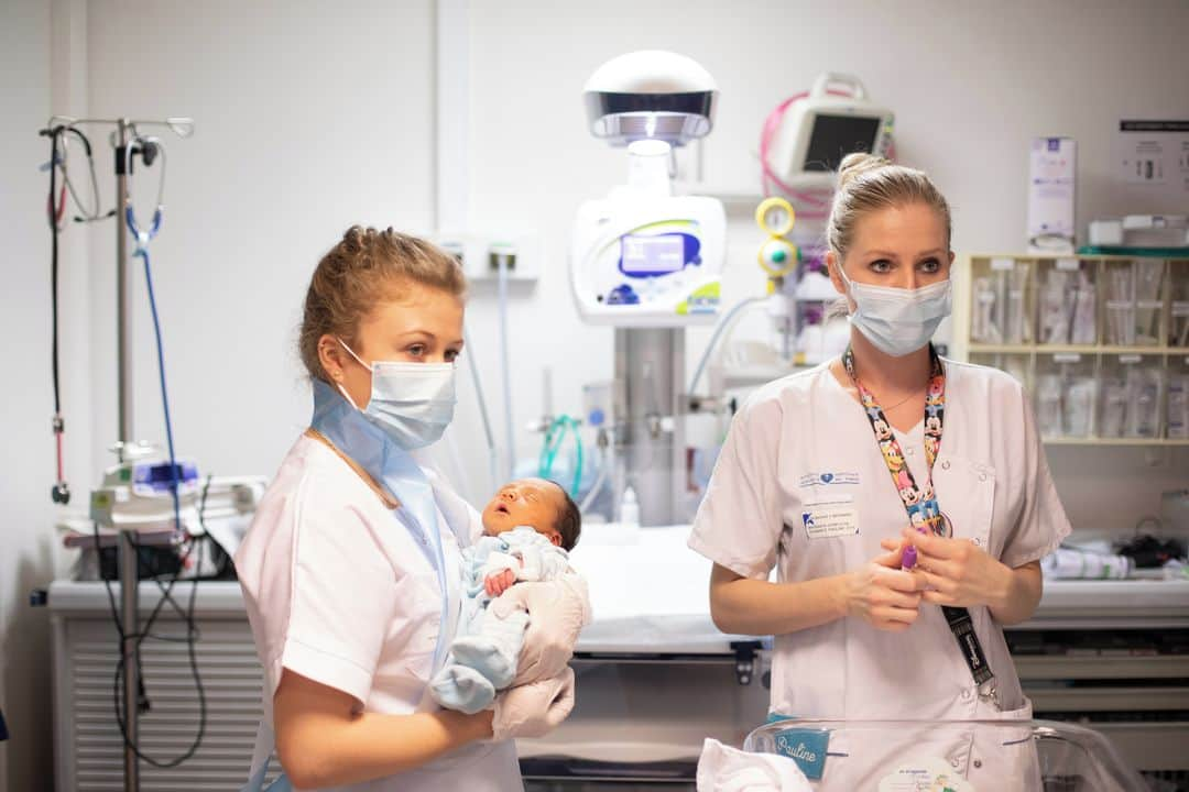 ルモンドさんのインスタグラム写真 - (ルモンドInstagram)「Le couloir de l’unité de néonatalogie de l’hôpital Bichat, dans le nord de Paris, brille encore de l’éclat de Noël. A l’entrée, un joli sapin, paré de guirlandes, des pochoirs floconneux aux fenêtres, et des dizaines de boules colorées suspendues au plafond. Dans la douce lumière de ce début janvier, Aurore Mandouki, puéricultrice, fait patienter un minuscule bébé qui attend son biberon. « Pourquoi tu me regardes comme cela ? Détends-toi », chuchote-t-elle, en caressant le nez de la petite fille, lovée dans la paume de sa main. Née prématurée, elle flotte encore dans son body bleu marine à pois taille « 00 » et agite ses petites mains en signe d’impatience.⁣ L’épidémie de Covid-19 semble ici bien lointaine, mais elle n’en bouscule pas moins la vie des jeunes parents, avec son cortège de règles. Assise dans la pénombre de la fin d’après midi, Charlène regarde attendrie sa petite Gemma, née il y a trois semaines, avec un mois et demi d’avance. Le papa patiente à l’extérieur, car seul un parent à la fois est autorisé à venir dans l’unité pour limiter les contacts entre familles. « Nous nous relayons, chacun une heure, jusqu’à ce qu’elle soit bien endormie. Et le 31 [décembre], nous sommes restés toute la nuit auprès d’elle », raconte la jeune maman.⁣ « Ces restrictions de visite, c’est ce qu’il y a de plus difficile pour les parents. Il y a même une période, au printemps, où c’était une heure par parent par jour », souligne Marielle Quellier, puéricultrice, en câlinant un minuscule bébé posé sur ses genoux, une multitude d’électrodes colorées dépassant de son body.⁣ -⁣ 1 : Dans le service néonatalogie de l’hôpital Bichat le 7 janvier. Nathalie Kassar et Marielle Quelle, infirmières puéricultrices⁣ 2 : Une maman donne le premier bain à son fils, sous le regard des infirmières⁣ 3 : Charlotte Berte, étudiante infirmière, et Pauline Schwartz, infirmière puéricultrice⁣ 4 : Aurore Mandouki, infirmière puéricultrice, nourrit un enfant prématuré⁣ 5 : Réunion au sein du service « suites de couche »⁣ 6 : Jennifer Le Croller, infirmière⁣ -⁣ Photos : Julie Balagué (@juliebalague) #PourLeMonde⁣ -⁣ #maternite #covid19 #hopital」1月12日 23時34分 - lemondefr