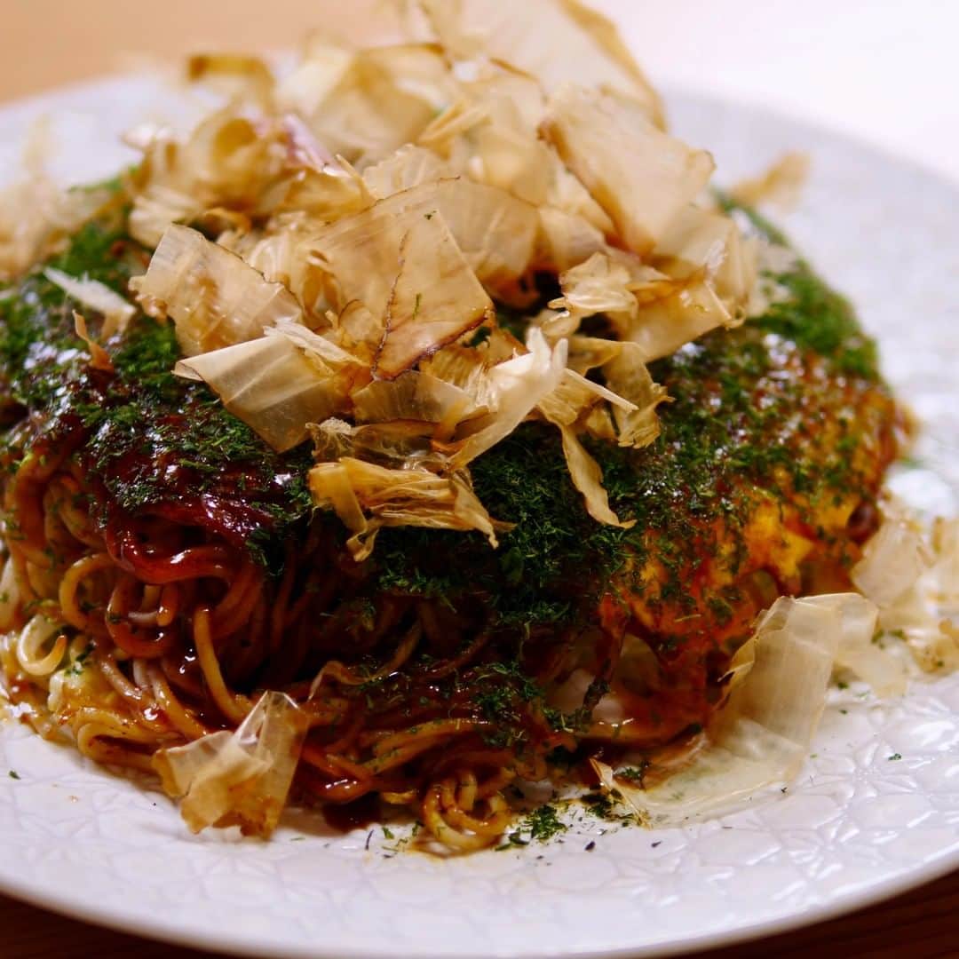 ロシアン佐藤のインスタグラム：「昨日の動画で食べたヘルシーモダン焼きのレシピだよー！ 低カロリーなパスタを中華麺に変身させるのがキモ！ 作ったら #ろしめし #ろしぴ つけて教えてねー🥺💝  〜 モダン焼きの作り方 〜  ＜材料 １人前＞ 水 1L A. 重曹 小さじ2 A. 塩 8g A. 糖質オフのパスタ 80g ごま油 小さじ1  玉子 3個 B. けずり粉 大さじ1 B. 千切りキャベツ 150g B. 桜えび 大さじ１ B. 小口切りネギ 20g B. 昆布茶 小さじ2 B. もやし 50g B. 切りイカ 2g B. そぎ切り鶏ささみ肉 100g  C. 中濃ソース 大さじ2 C. けずり粉 大さじ1  D. お好みソース（塩分・糖質オフだとさらにヘルシーだよ！） 適量 D. 青のり 適量 D. 鰹節 適量  ＜手順＞ 1. 鍋に１Lの水を沸騰させてAを加えて、正規の茹で時間のプラス２分長めに茹でる 2.麺をザルに移して水でしめたら、ごま油を絡める 3.250℃で加熱したホットプレートにクッキングシートをしいて玉子１個をまる〜く薄〜く広げる 4.その上にBを順にのせて最後に溶き卵１個をかけて５分くらい待つ 5.②をお皿に移してクッキングシートとお皿をかぶせ、ひっくり返す！ 6.生地をホットプレートに戻して、じ〜っくり焼く 7.待っている間に②の麺をホットプレートにのせ、Cをかけて混ぜたら、生地と同じ大きさの円形に整える 8.その上に生地をスライドさせて乗っける 9.もう１回、ホットプレートにクッキングシートをしいて玉子１個をまる〜く薄〜く広げた上に⑧をスライドさせて乗っける 10.⑤と同じことをもう１回やって、ひっくり返す！ 11.仕上げにDをかけて完成＼(^^)／  #おなかがすいたらモンスター #ロシアン佐藤 #ヘルシーメニュー #ロカボ #japanesefood #料理動画 #recipe #おうちごはん」