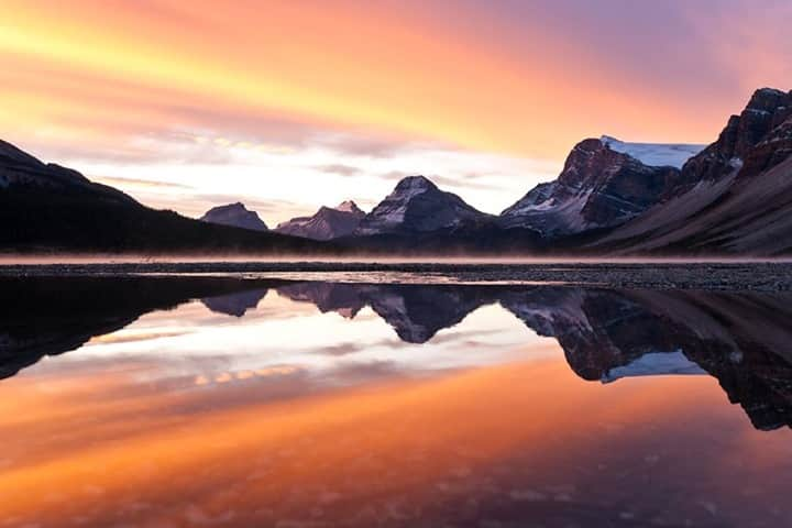 National Geographic Travelさんのインスタグラム写真 - (National Geographic TravelInstagram)「Photo by @daisygilardini / Bow Lake in Alberta’s Banff National Park is one of my favorite locations to visit during the fall. The tundra turns red, and at sunrise the lake is often steaming because of the temperature difference between air and water.  I woke up early on this morning to catch the first light, but I soon realized that the stiff breeze would not allow for a good reflection. Instead of going back to the cabin to sleep, however, I decided to look around and enjoy the moment. While walking along the beach, I noticed a puddle. The depression in the ground where the puddle formed was deep enough to shield the water from the breeze. The magic happened when I lay flat on my belly: The perfect reflection appeared.  Follow me @daisygilardini for more images and behind-the-scenes stories. #rockymountains #Alberta #landscapephotography #Canada #BanffNationalPark」12月23日 12時34分 - natgeotravel