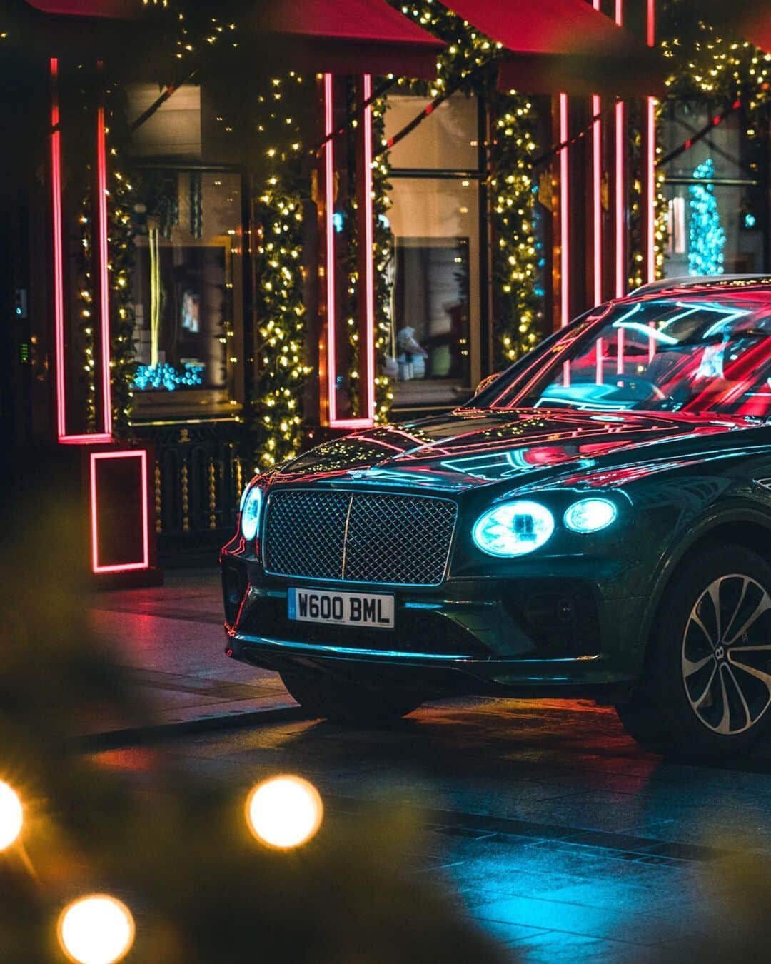 のインスタグラム：「On your mark, get, set, pose. The #NewBentayga V8 gets photographed by @m.visuals who took advantage of the city lights to capture some beautiful reflections against the Verdant paintwork.  Follow #BentleyFestiveLights for the next instalment coming this week. _ #Bentley Bentayga V8 WLTP drive cycle: combined fuel consumption: 21.7 mpg (13 l/100 km), combined CO₂: 294 g/km」