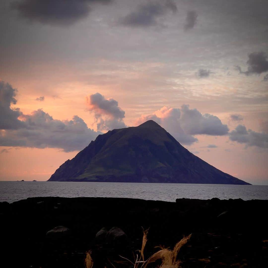林信行のインスタグラム：「An afternoon in Hachijo Island. #八丈島 の夕べ あまりの自然の美しさに一目惚れしました。 初めての八丈島滞在は3時間半。飛行機のマイレージプログラムとかに詳しい人に「250PP必要だった」と言えばピンと来るようなくだらないきっかけだったのですが(まあ、でも12月は本当に忙しかったので、これくらいの遊びは許してくださいー苦笑)、一番飛行時間短く行けそうだからと、全都道府県制覇して、次は「島」に目をつけていることもちょっとあって行ってみたら、あまりの美しさにやられてしまいました。最初は歩いて空港の周りだけでいいや、と近くのお蕎麦屋さんまで行き、そこから延々と1時間以上、タクシー捕まらないからと北側の港まで歩いてしまいました。その後、夕陽が落ちるのは反対側だと気がつきタクシーを呼び、運転手さんに「夕陽がきれいなところまで」と頼んで連れてきてもらった南原千畳岩海岸の夕陽も景色もあまりに美しく、次はもっと長く滞在しよう！と思っちゃいました。 ちなみに空港の外で半径5m以内に近寄った人は蕎麦屋のおじさまと、タクシーの運転手さんだけ。 全然、人とすれ違わないと思ったら、当然ながら皆、車だからなんですね。海岸まで歩いたと言ったら驚かれました😉  #畑中葉子　さんに3.5時間にしてはルートが完璧過ぎると驚かれましたが、次回はぜひ山の方にも攻め入りたい！  #HachijoIsland #八丈島 #shotOniPhone12ProMax (edited using built in features)」