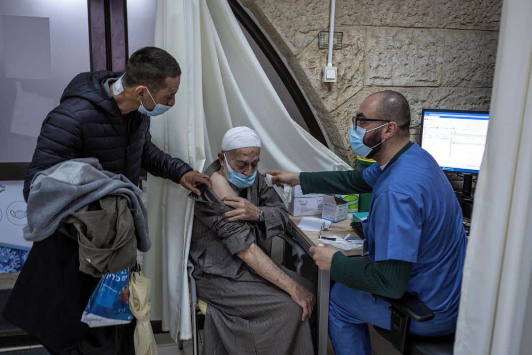 ルモンドさんのインスタグラム写真 - (ルモンドInstagram)「Mohamed Zahdeh déboutonne précautionneusement sa djellaba, à peine dissimulé par le rideau blanc qui isole quatre points de vaccination improvisés dans une petite salle d’une clinique de Jérusalem-Est. « Préférez-vous être piqué à droite ou à gauche ? Vous avez des allergies ? », demande l’infirmier, en préparant l’aiguille. Le vieil homme de 80 ans regarde droit devant lui pendant l’injection. « Il faut revenir le 31 janvier, pour la seconde dose », poursuit le soignant. « Si Dieu le veut », opine Mohamed Zahdeh en chaussant ses lunettes noires.⁣ ⁣ En deux semaines, plus d’un million d’Israéliens ont déjà reçu une première injection – sur neuf millions d’habitants. Quelque 300 centres ont été ouverts progressivement à travers le pays ; Israël est l’Etat qui vaccine le plus au monde. « Nous explosons tous les records », s’est félicité vendredi Benyamin Nétanyahou en saluant le millionième Israélien vacciné.⁣ -⁣ Vaccinations contre le Covid-19 à la clinique Clalit de Jérusalem-Est le 3 janvier. Photos : Tanya Habjouqa (@habjouqa) / Noor (@noorimages)#PourLeMonde⁣ -⁣ #Covid #coronavirus #vaccin #Israel」1月5日 0時27分 - lemondefr
