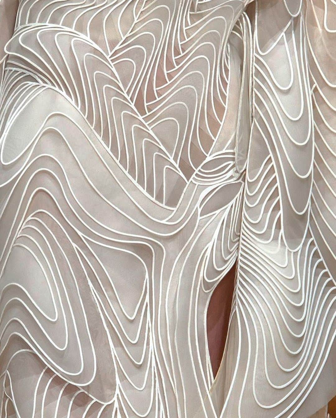 Iris Van Herpeさんのインスタグラム写真 - (Iris Van HerpeInstagram)「'Craftolution' ~ An exploration of the intricate dichotomies between structure and movement that encompass the poetics of each ethereal creation from the atelier ~ fusing layered lightness, three-dimensionality, and undulating volume to materialise the invisible forces that shape our world.    Look 1, 2: Syntopia dresses (2018) made of chronophotographic bird wing lines that are lasercut from mylar and white cotton, to then be heat-bonded to transparent layers of green and copper dyed organza, to flow like a time-lapse motion. Look 3: 'Glitch' dress (2017) made from a fine black silk and an expandable lasercut mylar fabric in collaboration with @Philip.Beesley. Look 4: 'Labyrinthine' gown (2020) made from 3D lasercut metallic dendrites that are heat bonded to blossoming leaves of white translucent organza, to then be hand-stitched onto lasercut pearlescent skeletal labyrinths, creating a vibrating exoskeleton of weaving waves. Look 5: 'Symbiotic' Asymmetric Kimono dress (2019) made from white silk panels that are layered and heat-bonded into a fine 3D lasercut lace of white mylar and cotton, creating hybrid bird patterns. Look 6: 'Lucid' black dress (2016) made from transparent hexagonal lasercut elements that are hand-connected with translucent flexible tubes, creating a glistering bubble-like halo around the body ~ in collaboration with @Philip.Beesley. Look 7: 'Nautiloid' dress (2020) made from cellular deep-sea aquarelles of blues and greens that are oil-painted by @SheleeArt, 3D layered transparent lasercut PetG bubbles are then heat-bonded to multiple transparent digitally printed glass-organza halos. Look 8: 'Aeolian' dress (2018) made from transparent blue organza that is pleated into half-wheel pliseé panels that are liquid-coated, transparent folds cross each other in different directions like glass wings in thin air.  #irisvanherpen #couture #archive」1月7日 1時19分 - irisvanherpen