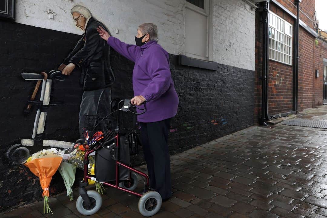 ルモンドのインスタグラム：「Il était devenu un héros après avoir réuni une somme record pour les soignants britanniques pendant le premier confinement. Le vétéran de la seconde guerre mondiale Tom Moore est mort, mardi 2 février, à l’âge de 100 ans, après avoir été diagnostiqué positif au Covid-19, a annoncé sa famille.⁣ Le 6 avril 2020, alors âgé de 99 ans, Tom Moore s’était fixé comme modeste objectif de réunir 1 000 livres (1 100 euros) durant le premier confinement pour aider le service de santé public (NHS) débordé par les malades du Covid-19, s’engageant à parcourir avant son centième anniversaire cent longueurs de son jardin, dans le sud de l’Angleterre.⁣ Petite bulle de légèreté au milieu d’une année morose, l’image du vétéran penché sur son déambulateur et avançant coûte que coûte avait galvanisé les Britanniques et leur sentiment de reconnaissance envers les soignants. Les dons avaient alors afflué et Tom Moore avait, finalement, recueilli 33 millions de livres (37 millions d’euros), le plus gros montant jamais récolté par une personne seule lors d’une marche caritative. « La dernière année de la vie de notre père n’a été rien de moins que remarquable. Il a rajeuni et a vécu des choses qu’il n’avait jamais imaginées en rêve », ont ajouté ses filles.⁣ Le premier ministre Boris Johnson, la reine Elizabeth, ou encore Dominic Raab, le ministre des affaires étrangères, ont exprimé leurs condoléances à la famille de ce héros britannique, immensément populaire dans son pays.⁣ -⁣ Une femme vient déposer une gerbe de fleurs devant une peinture murale représentant le vétéran Tom Moore à Pontefract, au Royaume-Uni, le 3 février. Photo : Lee Smith (@instamackem)/ Reuters (@reuters)⁣ -⁣ #TomMoore #NHS」