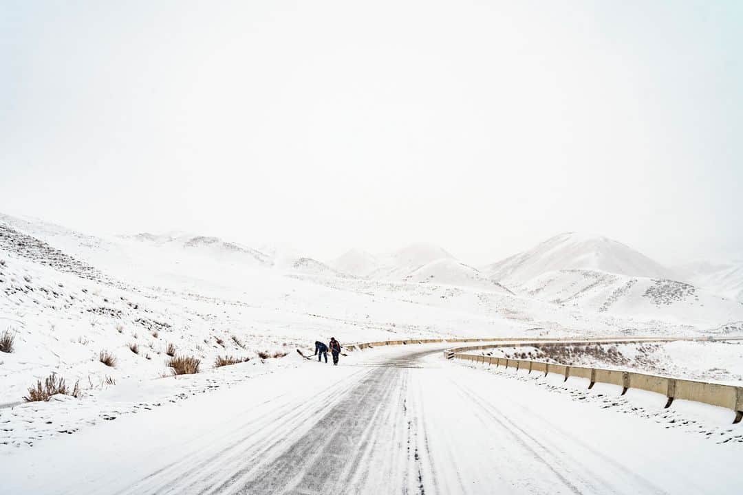 ルモンドさんのインスタグラム写真 - (ルモンドInstagram)「La route déroule son ruban d’asphalte à travers les steppes enneigées, entre l’épine dorsale du Tian Shan, chaîne de géants tutélaires drapés de blanc, et une rangée de collines de terre rouge ciselées par l’érosion. C’est là, sur le bas-côté, à 100 kilomètres du col de Torougart et de la frontière chinoise, et à 400 kilomètres de Bichkek, la capitale du Kirghizistan, sur un rectangle plat de deux kilomètres sur un, que devait s’ériger la « zone industrielle, commerciale et logistique sino-kirghize d’At-Bachy ».⁣ C’était compter sans la dizaine de milliers d’habitants d’At-Bachy, le chef-lieu de district, situé à cinquante kilomètres à l’est. Ils vivent du petit commerce et, surtout, de l’élevage.⁣ « Ici, il n’y a pas assez de travailleurs spécialisés. Alors d’où viendraient-ils, ces milliers d’employés ? De Chine, pour moitié d’entre eux ! Et les Kirghiz n’auraient eu que des postes subalternes, le gardiennage. La zone est en amont des villages, à l’ouest, d’où viennent le vent et la rivière : ça nous aurait pollués. Nos ressources sont bien trop limitées », résume Junusaliev Mederbek, 57 ans, réparateur en électronique, dans son gros anorak, chapka sur la tête, dans la petite pièce chauffée d’un restaurant d’At-Bachy où une matrone sert le thé.⁣ -⁣ 1-9 : La route principale menant d’Al-Bachi, au Kirghizistan, au col de Torougart, à la frontière chinoise, le 12 janvier 2021⁣ 2 : De l’ex-future base industrielle chinoise ne restent plus qu’une station-service et un motel pour routiers⁣ 3 : Junusaliev Mederbek (à gauche) est l’un des meneurs de la contestation contre le projet de zone industrielle chinoise à At-Bachy. Il lit un poème à Guljan Aitbaeva, dans un restaurant de la ville, le 13 janvier, pour la remercier de son soutien⁣ 4 : Des chasseurs ont capturé des loups ayant attaqué le bétail d’un village reculé⁣ 5-6 : À Bichkek le 10 janvier, le bazar Madina est construit en containers empilés⁣ 7 : Un panneau vantant les « nouvelles routes de la soie » chinoises⁣ 8 : Deux fillettes observent leur père réparer sa voiture devant le motel pour routiers d’At-Bachy⁣ -⁣ Photos : Yam G-Jun (@yamgjun) #PourLeMonde⁣ -⁣ #Kirghizistan #routedelasoie #economie」2月6日 20時00分 - lemondefr