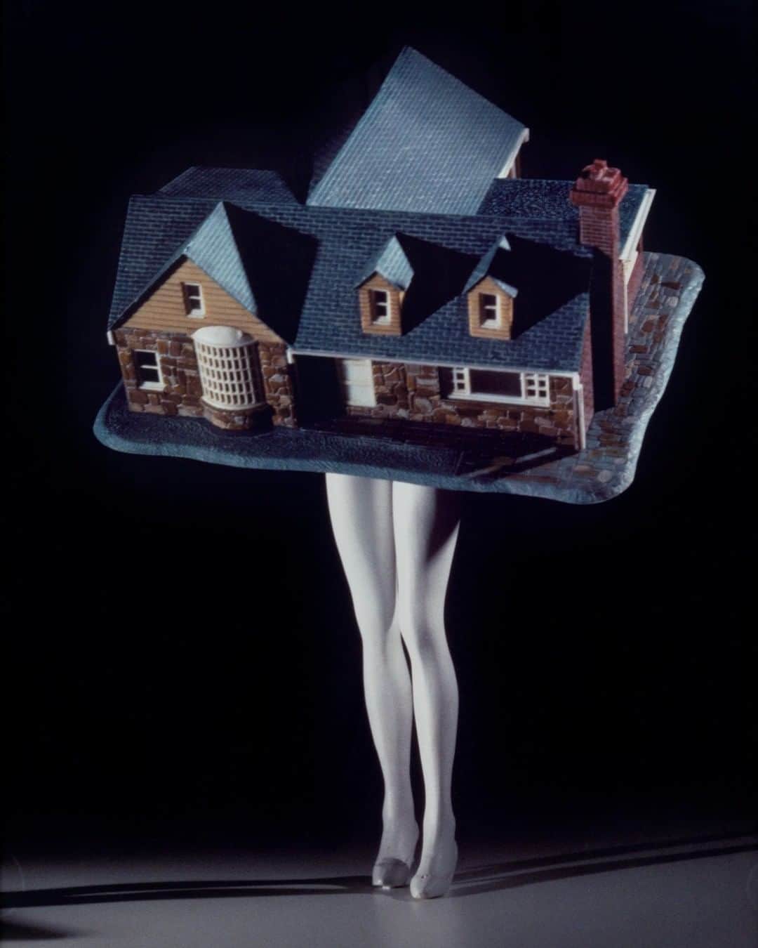 ニューヨーク近代美術館のインスタグラム：「TFW you haven't left the house since March.  In her "Walking Objects" series from the late 1980s, #LaurieSimmons endows commercial objects with human personalities by giving them legs and presenting them at a human scale. This print is almost six feet tall!  Isolated against a seamless backdrop under the dramatic artificial light of a stage or studio, the figures in these photographs are perfect and alluring. In "Walking House," sleek legs support a toy suburban house of the sort the young woman might have grown up in and in which—after marriage—she is destined to live.  Like many of her contemporaries, @lauriesimmons has used the material of popular culture to probe and often debunk its social values. But the critical spirit of her photographs is colored with nostalgia. Later she recalled, "I was simply trying to recreate a feeling, a mood . . . a sense of the fifties that I knew was both beautiful and lethal at the same time."  📸 Laurie Simmons, "Walking House" (detail), 1989. Gelatin silver print.© 2021 Laurie Simmons #MoMACollection」