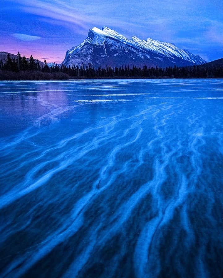 National Geographic Travelさんのインスタグラム写真 - (National Geographic TravelInstagram)「Photo by @kahliaprilphoto / Veins in the ice snake their way through the frozen lake as the sun sets over Mount Rundle in Banff National Park.」1月15日 16時39分 - natgeotravel