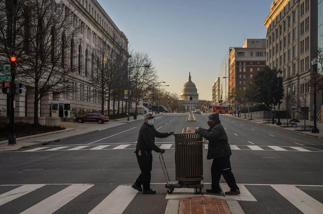 National Geographic Creativeのインスタグラム：「Photo by @andreabruce / Washington, D.C., government workers move trash cans on the Hill for security reasons.  Tuesday, the day before the 2021 presidential Inauguration, the city was quiet, with more street closures and an absence of the D.C. bustle one normally experiences during morning rush hour.」