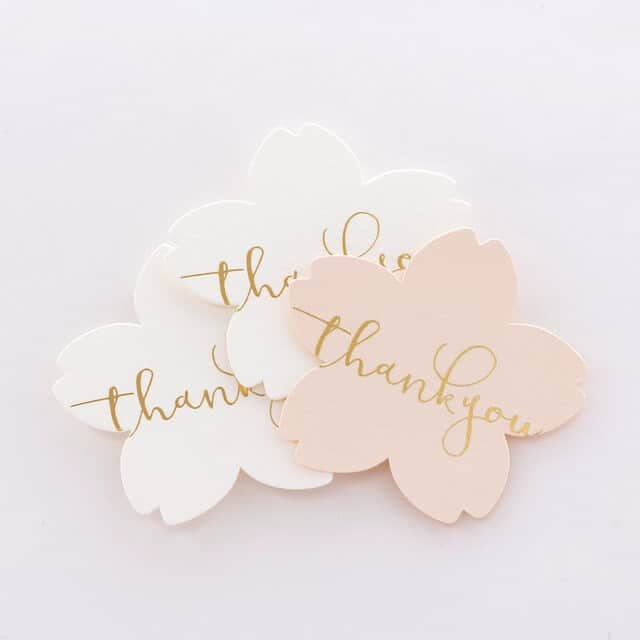 ダブルエムのインスタグラム：「桜型のカタチに金箔押しで「Thank you」の文字。  メッセージカード サンキューカード アクセサリー台紙　など使い方次第でお楽しみいただけます。  やや厚紙の白紙「ホワイト」と 薄く淡い「ピンク」の2色の紙をご用意しました。  ★★★ 枚数：10枚　1セット サイズ：W70mm×H66mm  【商品の詳細・ご注文】﻿ ①この投稿をInstagramで閲覧されている場合﻿ 商品画像をタップしてミンネで購入♪﻿  ②この投稿をFacebookやWEBブラウザで閲覧されている場合 以下のリンクから公式HPの商品ページに進めます。  桜のカード／アクセサリー台紙 https://minne.com/items/17838548  【お問い合わせ】 お探しの商品が見つからない場合など、公式サイト内「お問い合わせフォーム」よりお気軽にお声がけください。専門スタッフが対応いたします。 ※土日祝定休、お問い合わせ対応は10〜18時となります。 ※Instagramのコメント・メッセージでのご対応は行っておりません。  *・。*・。*・。*・。*・。*・。*・。  箔押し印刷とは、メタリックの輝きを持つ金箔、銀箔のシートを熱と圧力で紙に転写する特殊印刷のこと。  ダブルエムの箔押し印刷は、すべて職人の手作業。 デザインから金属の版を作成し、一枚一枚を手押しで加工します。  花嫁の手紙やハートの様サンキュータグは、CLASSYやminne、Creemaなどの各メディアで取り上げられ、花嫁様やアクセサリー作家様にたくさんのご依頼を頂いております。  うまく仕上がるのかな 少ない数でも注文できるのかな 今から依頼しても間に合うのかな  そんな心配がございましたら、まずは公式HPのお問い合わせフォームより気軽にお問い合わせください。 専門スタッフがご対応させていただきます。  ぜひ、一緒に楽しむお洒落なペーパーアイテム作りをしましょう。  *・。*・。*・。*・。*・。*・。*・。  #アクセサリー台紙 #ダブルエム #wmjapan #箔押し #台紙 #アクセサリー台紙 #ピアス台紙 #タグ #ハンドメイドアクセサリー #ハンドメイドピアス #ハンドメイドイヤリング #ハンドメイド好きさんと繋がりたい #ハンドメイド雑貨 #ハンドメイド部 #ハンドメイドイベント #ハンドメイドアクセ #ハンドメイドジュエリー #ハンドメイドネックレス #ハンドメイド販売 #ハンドメイド作家 #ハンドメイド作品 #ハンドメイド作品 #ハンドメイドショップ #ハンドメイド小物」