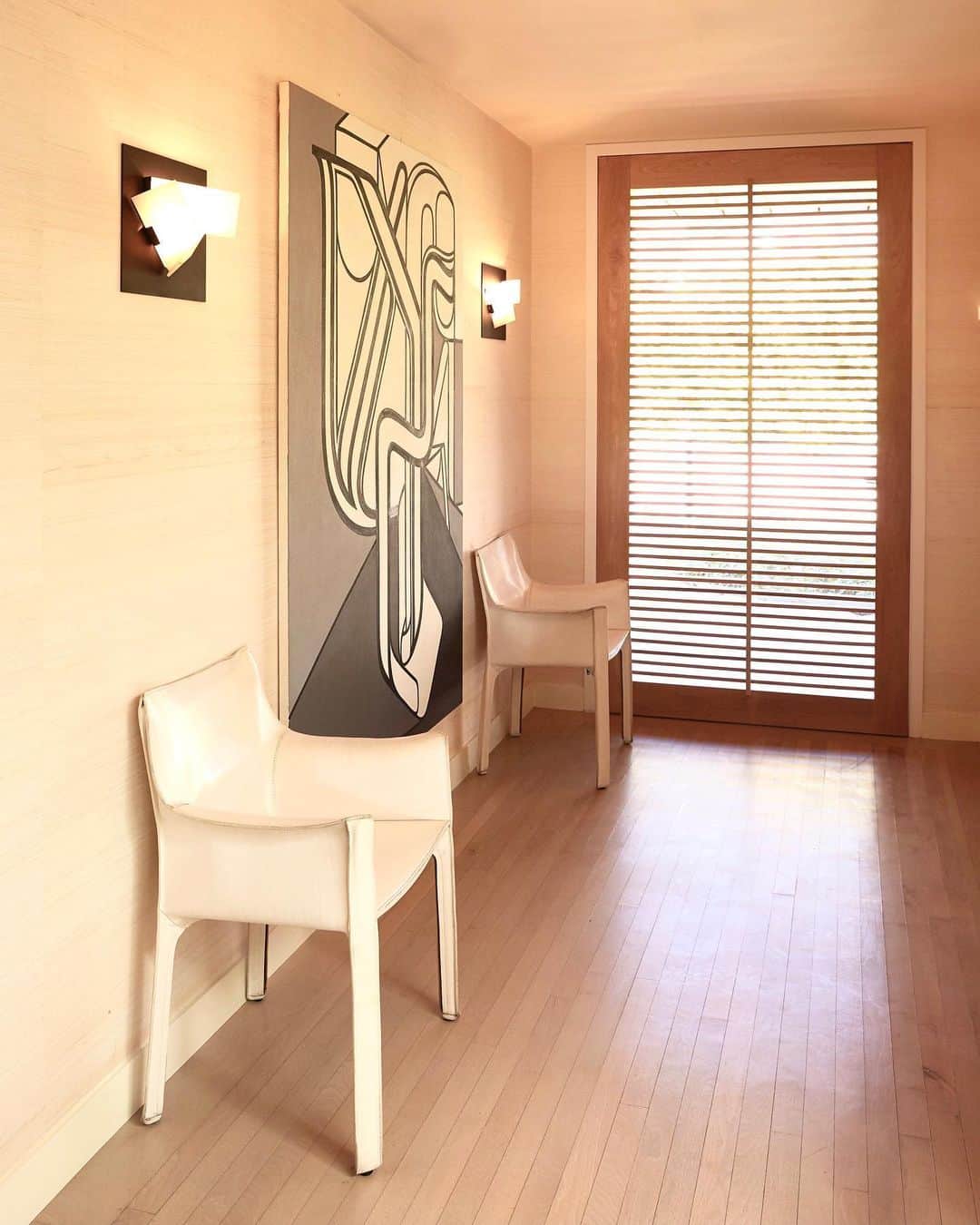 ケリーウェアスラーのインスタグラム：「PRIVATE PASSAGE. Passages can become intimate nooks within the home by adding dimension to a space. A painting by @bartexposito and a pair of sculptural Mario Bellini chairs topped with Pierre Chareau geometric sconces create a place for repose in the passage. XK」