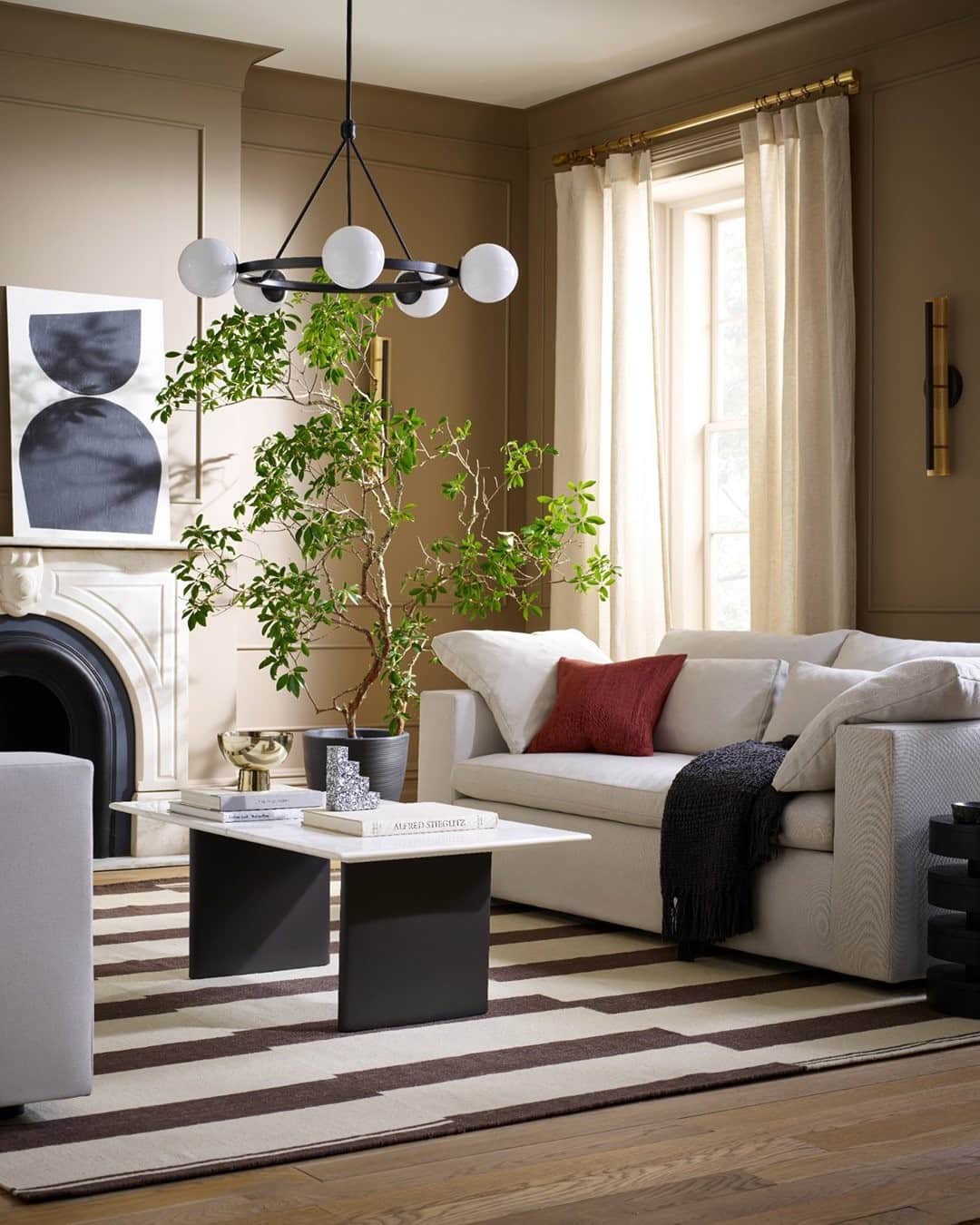 のインスタグラム：「A chic and sophisticated living room ✨ Start with a balanced palette of black and white, then create warmth with the in-between: sand-colored walls, hints of brass and throw pillows in shades of sunset.  Tap the link in our bio to see more of this space! (Wall color: Woodbridge SW 9618 by @sherwinwilliams)」