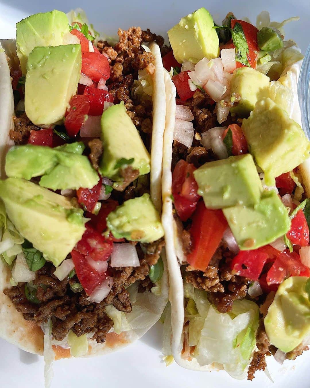 Sascha Barbozaのインスタグラム：「Tex-Mex Tacos! Quedaron riquísimos🤪aunque no están ni cerca de los tacos deliciosos tradicionales mexicanos. Son más estilo estilo taco Bell. Honestamente no sabía cómo tomar la foto porque soy una grosera y les puse demasiado relleno pero estaban riquísimos.   Para la carne. 1/2 kilo de carne de res magra molida. Se sofríe con un poquito de aceite y la condimente con taco seasoning y un poquito de comino y sal. Pero pueden sustituir ese condimento por una cucharadita de chile en polvo, una cucharadita de ajo en polvo, una cucharadita de comino, media cucharadita de paprika, sal y pimienta.   Pico de gallo.  En cuadros pequeños pique: 3 tomates, 1 cebolla, 1/2 taza de cilantro. lo mezcle y le agregué dos limones exprimidos, sal y pimienta.   Lo demás no tiene mucha ciencia, calenté en un budare tortillas de trigo y de maíz, la tortilla de maíz a nivel nutricional es de mejor calidad pero elijan la que más les guste siempre y cuando controlen la cantidad, le agregamos en la base un puré de caraotas rojas, lechuga, la carne, pico de gallo y aguacate! .  Comer  saludable no tiene porque ser aburrido, puedes darle un giro a recetas tradicionales sustituyendo ciertos componentes que ayudan a elevar su perfil nutricional y bajar calorías.  . Tampoco deben temerle a los carbohidratos por mucha dieta de moda que te diga lo contrario, es gasolina para tus músculos, cerebro, si lo comes en la cantidad adecuada en horas cercanas a tu entrenamiento te ayudan a reponer energía, regenerar masa muscular, mejorar el funcionamiento de tiroides, elevan serotonina etc. Y recuerda que cada cuerpo es distinto, no todos necesitamos la misma cantidad y no todos toleramos los mismos carbohidratos. Tienes que aprender que funciona para ti y que puedes sostener a largo plazo.」
