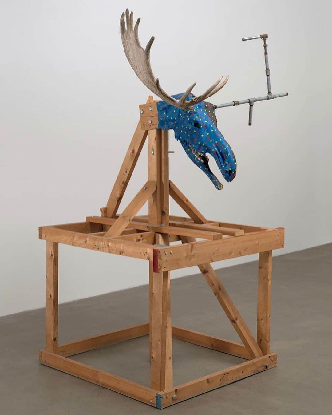 ニューヨーク近代美術館のインスタグラム：「Is that a moose at MoMA?  Working in New York in the 1980s, artist #JimmieDurham foraged for bones and other materials to create patchwork figures. For this assemblage, he embellished a moose skull with paint and replaced one of its horns with a metal pipe. Found in a dumpster near @stjohndivinenyc, the skull is mounted on a wooden structure that at once functions as the moose’s skeleton and resembles the scaffolding encountered on city streets.  At the link in our bio, read a new interview with the artist and curator @paulinapobocha about poetry, activism, and Durham's uncanny knack for breathing new life into found materials. See "The Cathedral of St. John" and more works by Durham in the #MoMACollection Gallery 207: Assembly. — [Jimmie Durham. "The Cathedral of St. John the Divine in Manhattan is the World’s Largest Gothic Cathedral. Except, of course, that it is a fake; first by the simple fact of being built in Manhattan, at the turn of the century. But the stone work is re-inforced with steel which is expanding with rust. Someday it will destroy the stone. The Cathedral is in Morningside Heights overlooking a panoramic view of Harlem which is separated by a high fence." 1989. Moose skull with antler, metal pipe, wood, and paint]」