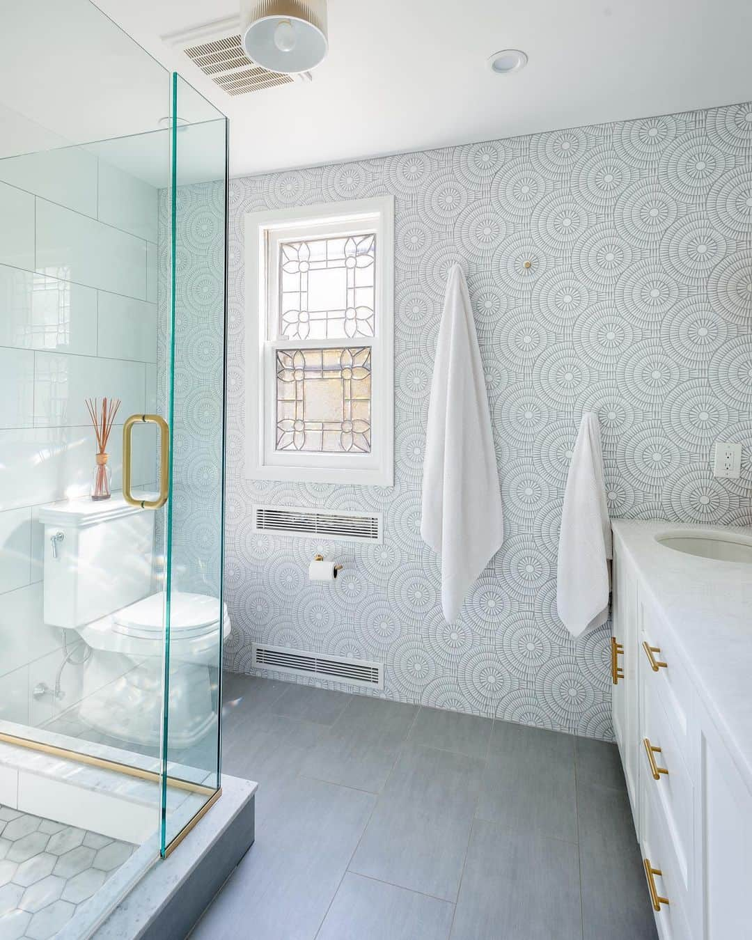 Sweeten Homeのインスタグラム：「Outdated and slated for a full redo, this bathroom received a luxurious update with glass-walled showers, gleaming fixtures, double-sink vanity and statement lighting.⁠⠀ ⁠⠀ Floor and wall tile: @artistic_tile Sink & drawer pulls: @kohler」